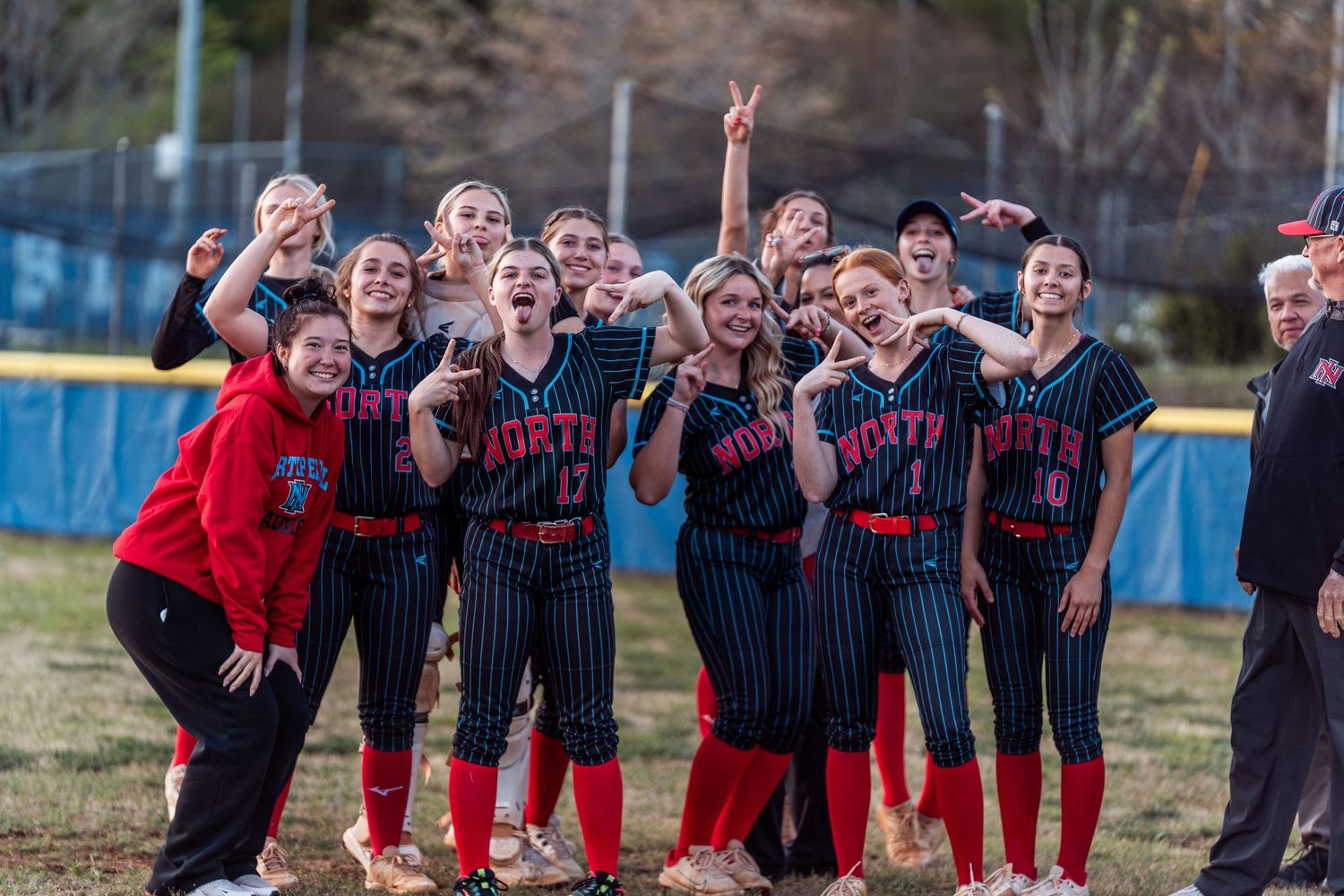 A softball team in pinstriped uniforms celebrates together on the field during a game.