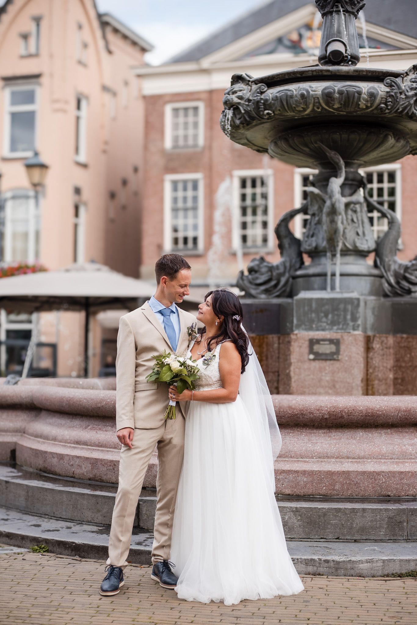 Newlywed couple shares romantic moments around an ornate fountain at the square in Gorinchem