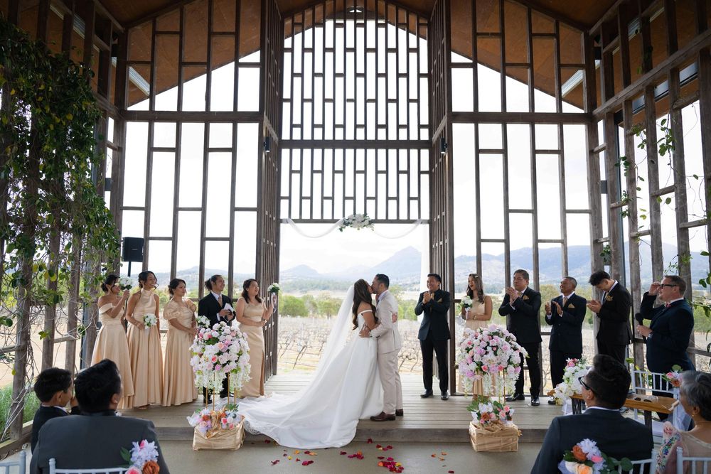Bride and groom kissing at altar in stunning open-air chapel with mountain views.