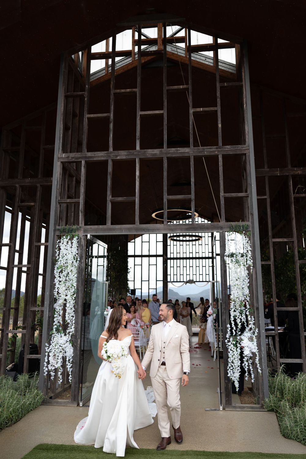 Bride and groom exiting rustic industrial wedding chapel holding hands after ceremony.