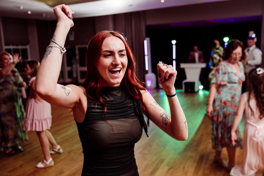 People dancing and having fun at a wedding reception with colorful lighting and a festive atmosphere.
