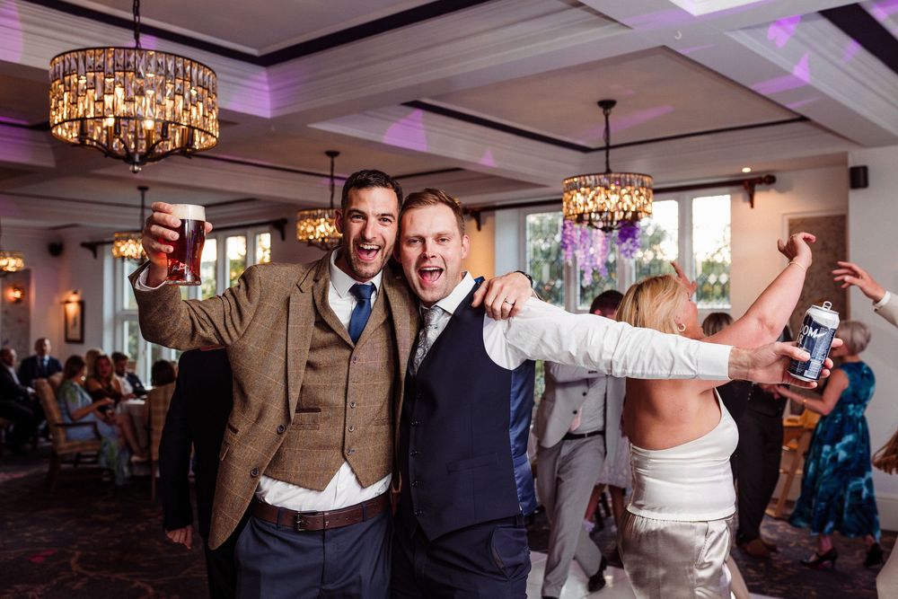 Guests celebrate joyfully at an elegant wedding reception with crystal chandeliers and purple mood lighting.