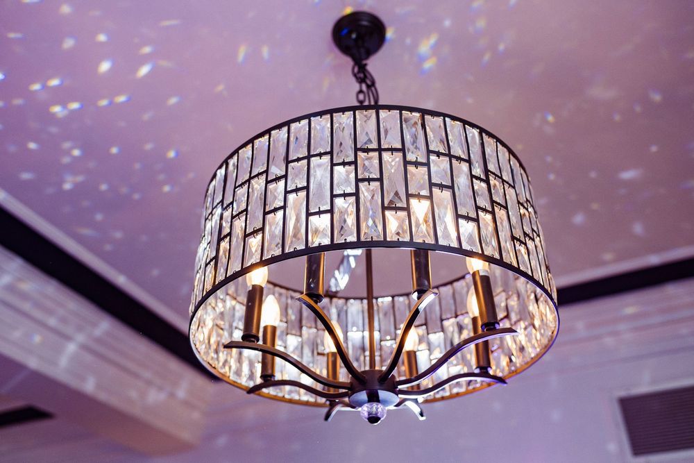 Crystal chandelier creates a sparkling pattern of light reflections on the ceiling of an elegant room.