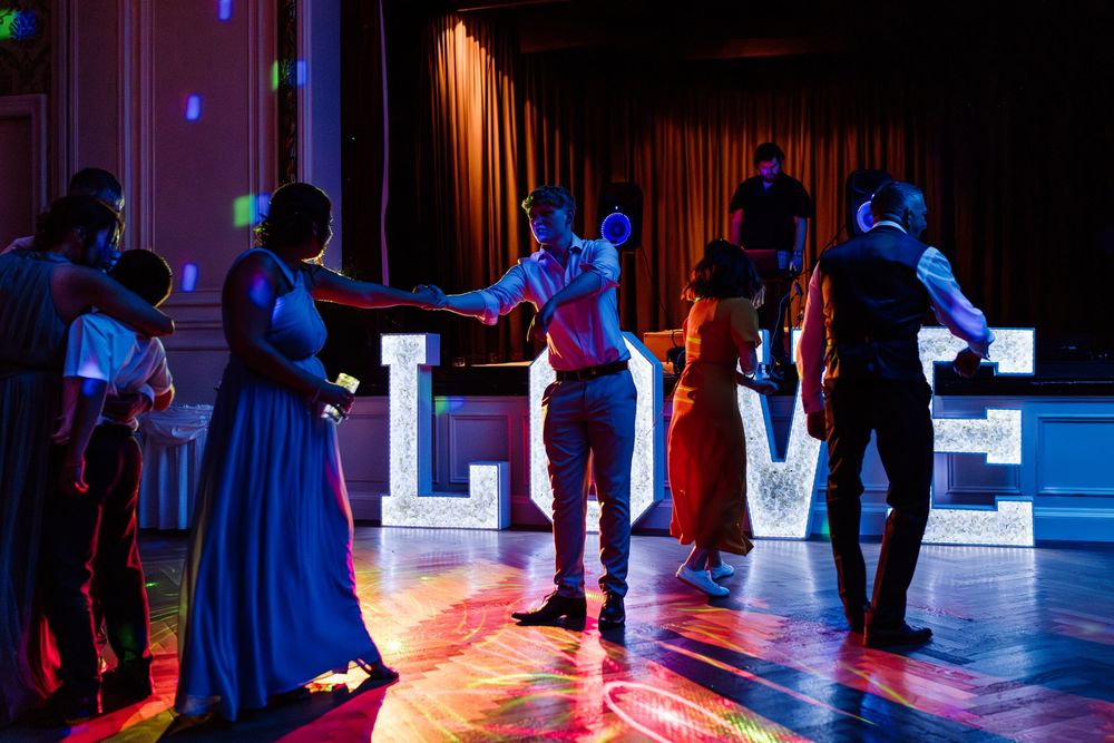 People dancing at a nightclub with colorful blue and red lighting on the dance floor.
