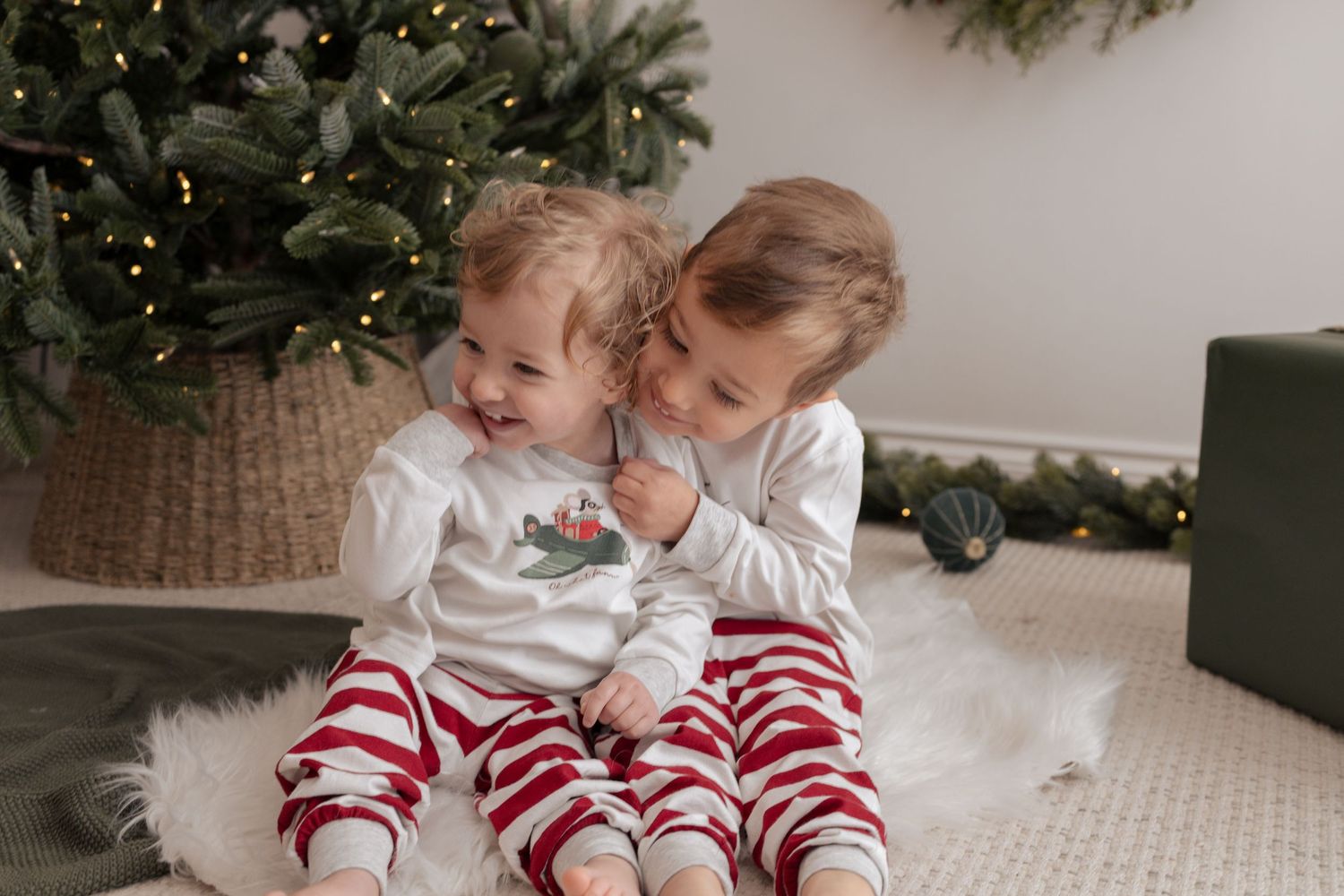 Family lying on white carpet near decorated Christmas tree in matching holiday pajamas. Photography in Buckinghamshire.