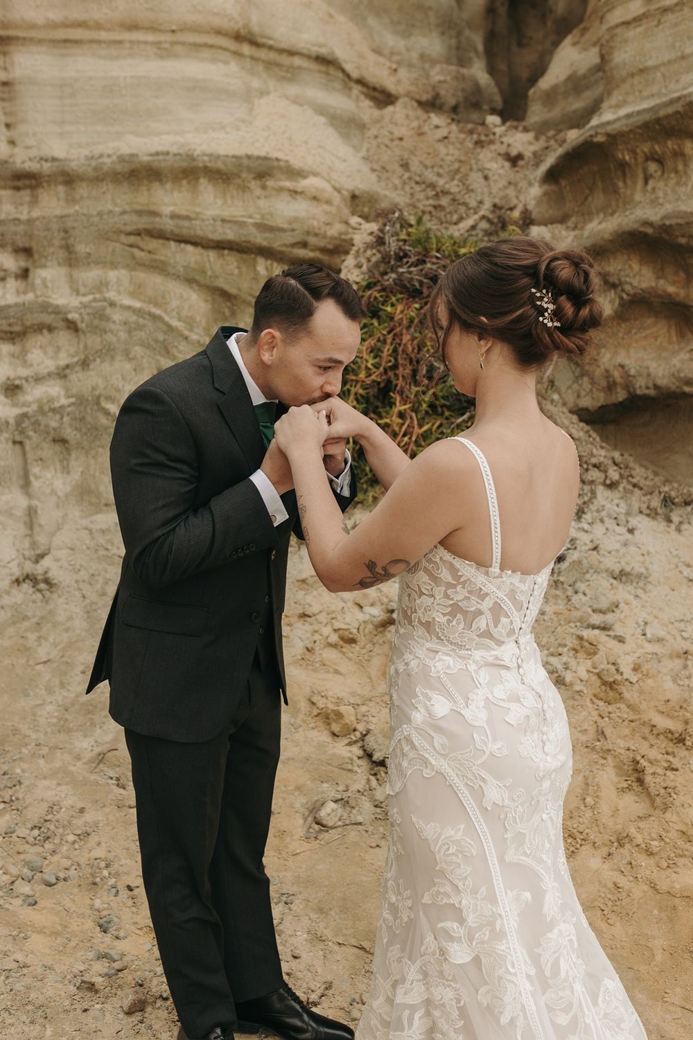Romantic wedding couple shares intimate moment against weathered rock wall backdrop at Calafia Beach Park in San Clemente..