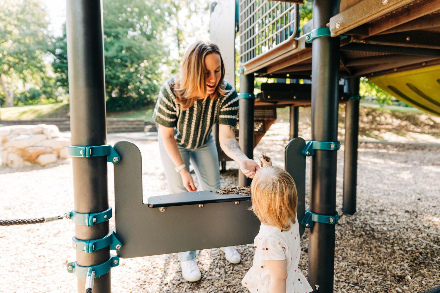 A mom and daughter play Ice Cream Parlor with mulch at a Charlotte playground.