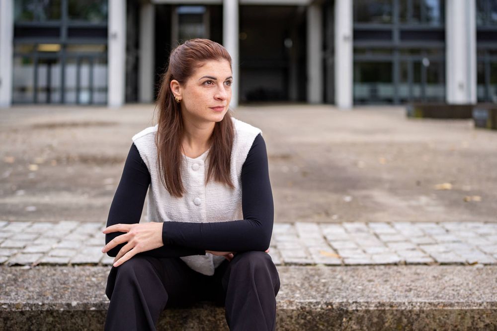 Professional in business attire sitting on outdoor steps while looking thoughtfully into the distance.