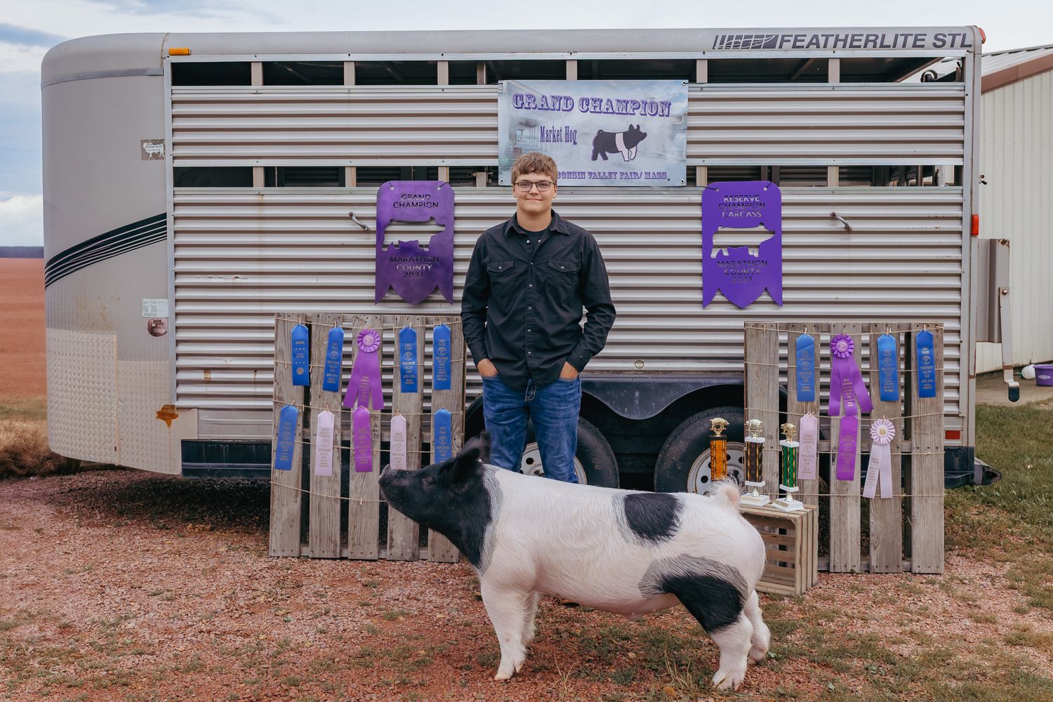 Senior standing with pig showing awards during senior session to showcase their high school achievements