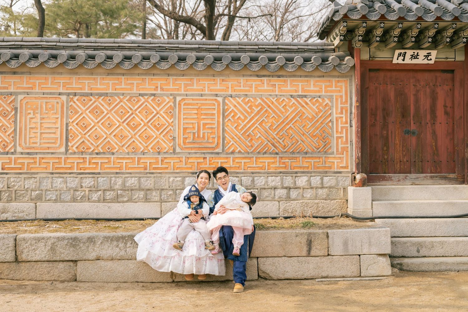 Traditional Korean palace wall with decorative patterns and stone foundations stretches along a scenic walkway.