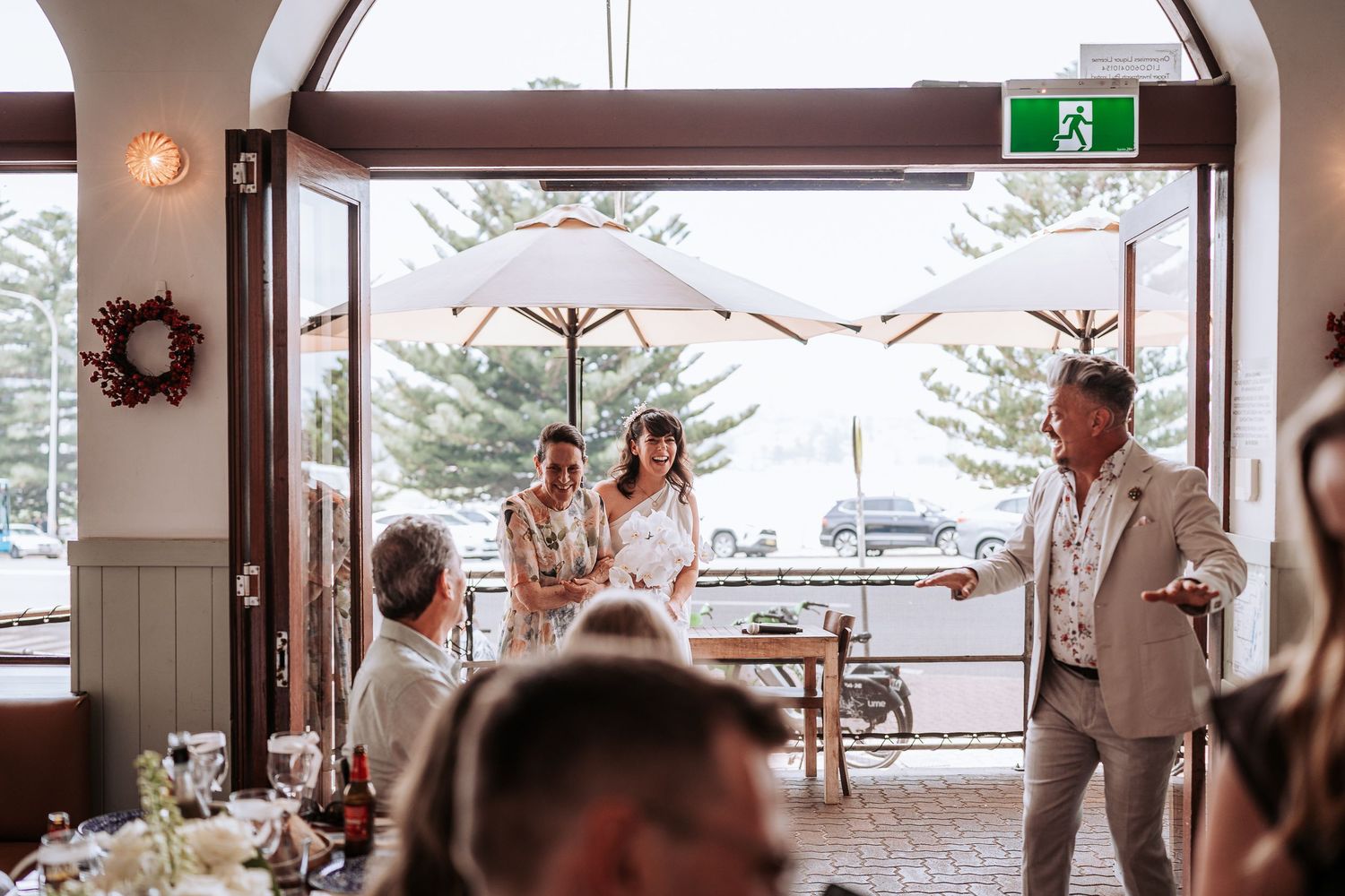 Wedding reception celebration at a coastal venue with umbrellas and decorative wreaths.