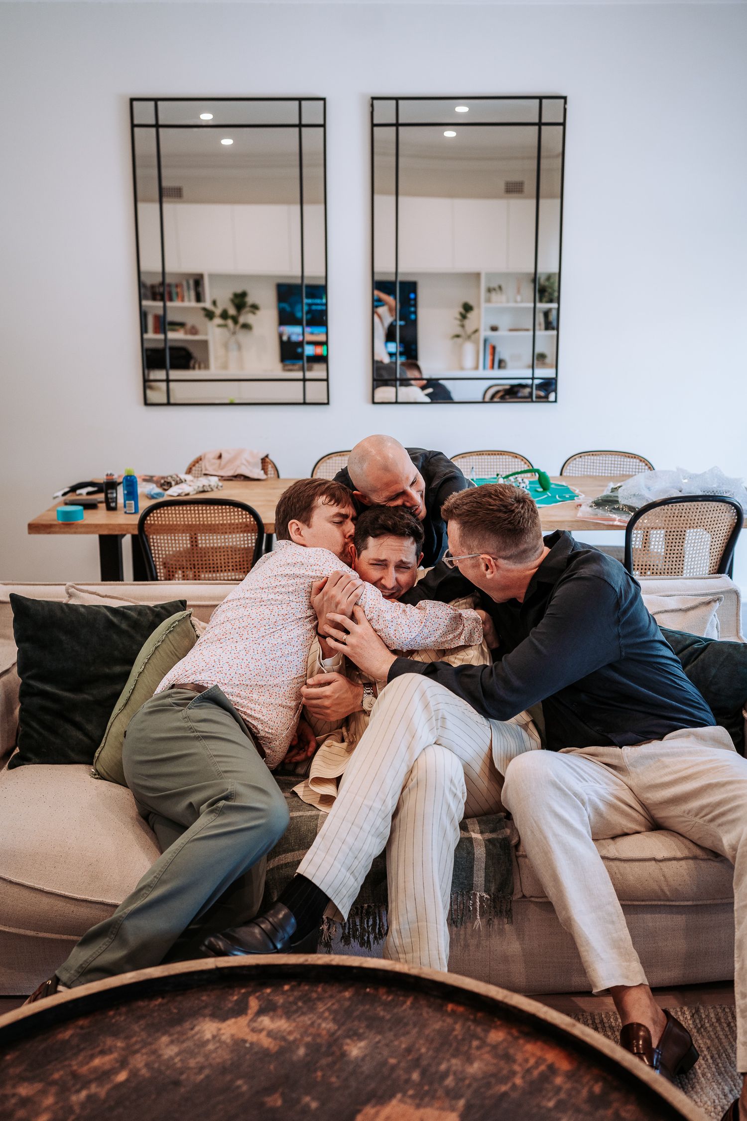 Progressive sequence showing people playfully falling onto a gray couch in a modern living room setting.
