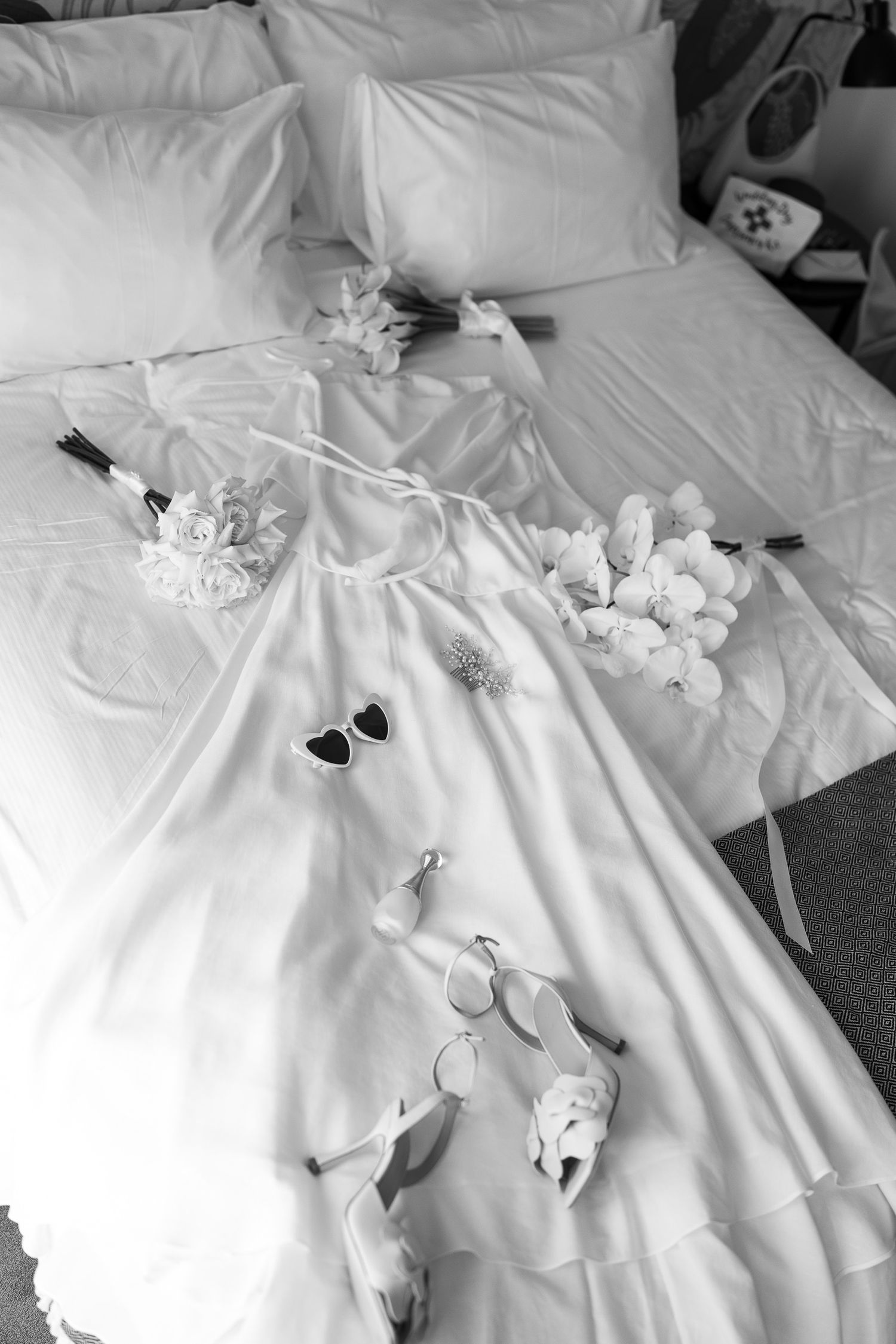 Close-up shots of white wedding dress details laid out on a bed.