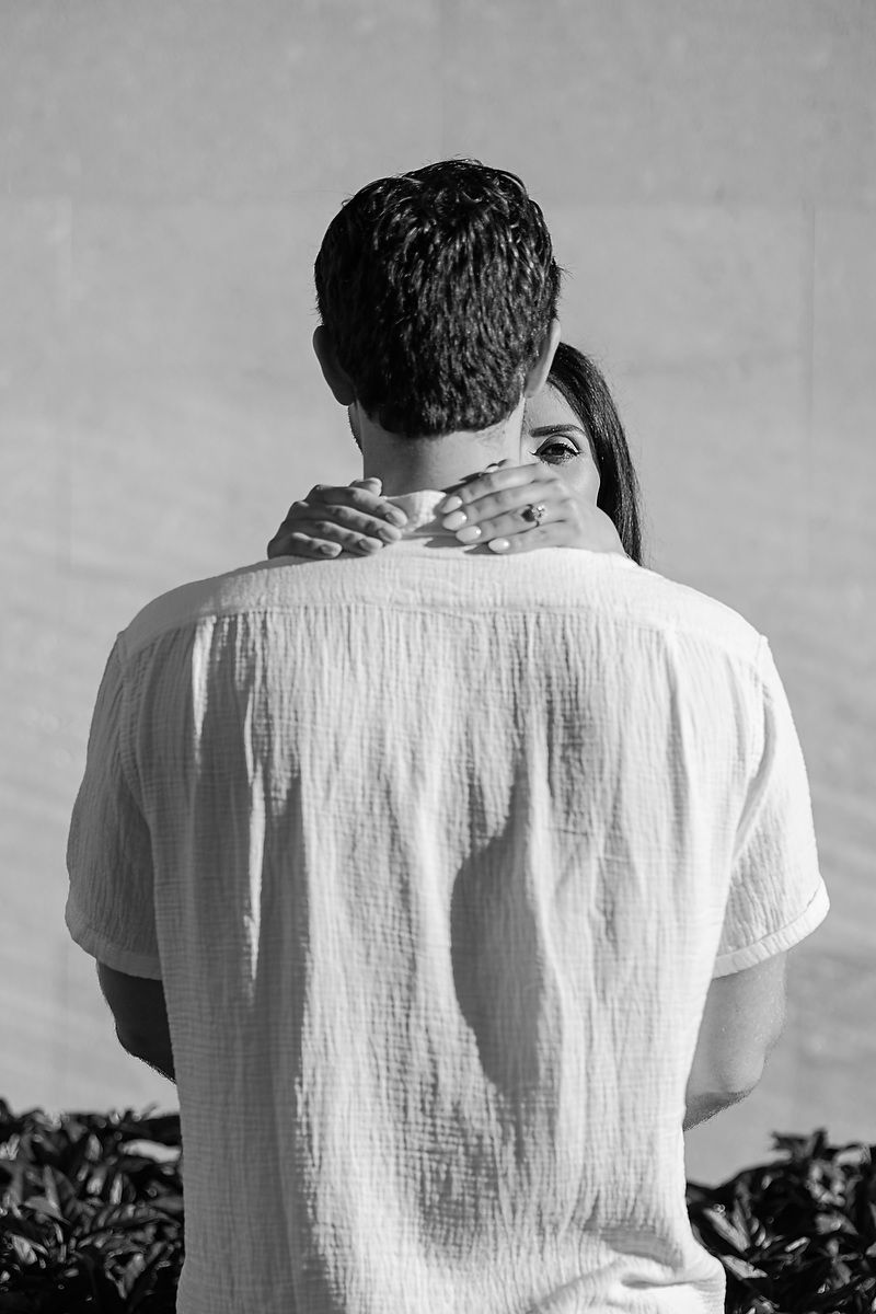 Black and white image showing back view of person in white shirt against gray background.