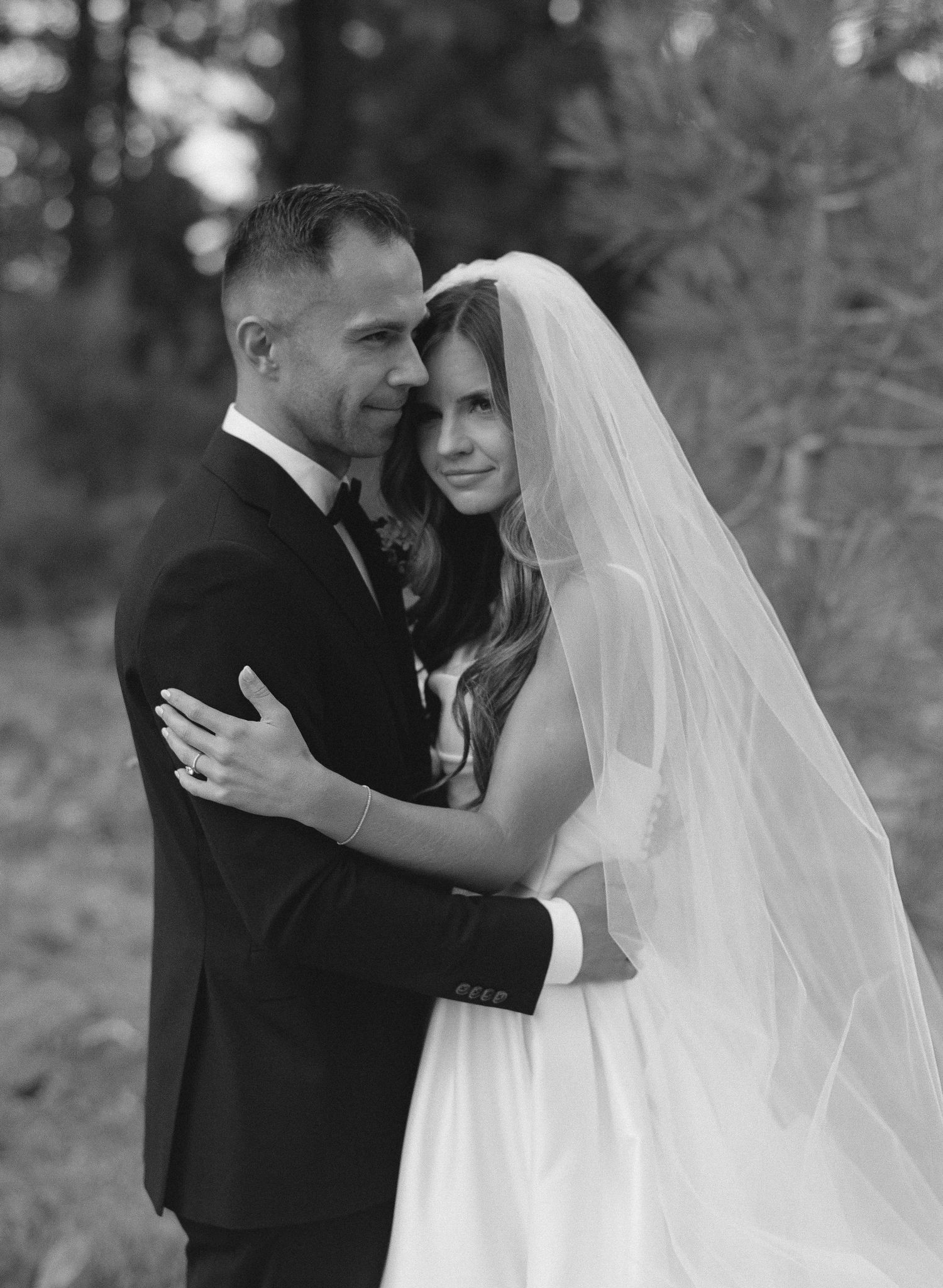 A romantic black and white wedding photo series showing tender moments between a bride and groom embracing outdoors.