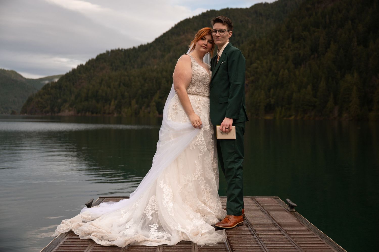 Two women embrace each other on a dock on Lake Crescent in Olympic National Park, celebrating their Pacific Northwest adventure elopement