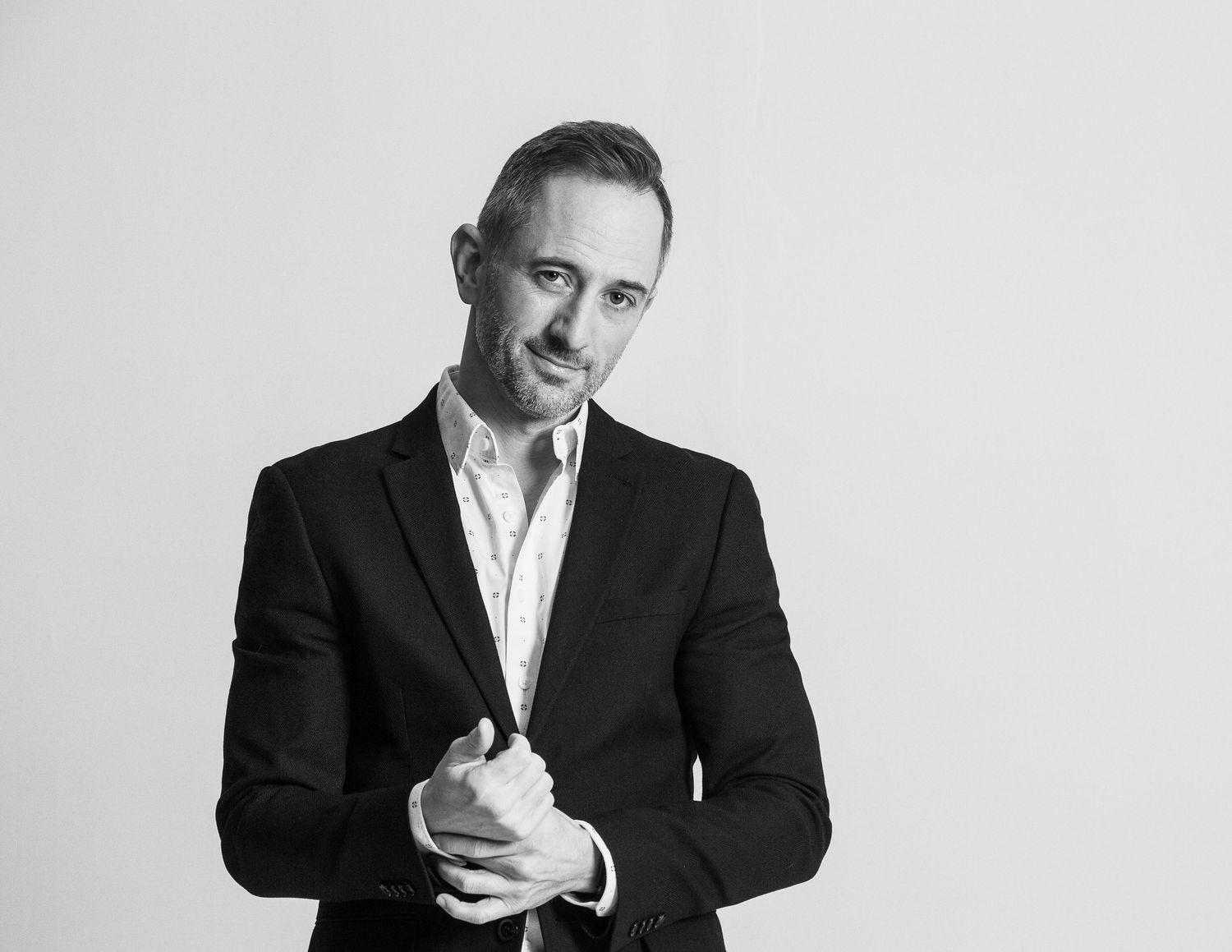 Black and white portrait series showing professional in dark suit jacket striking different expressive poses.