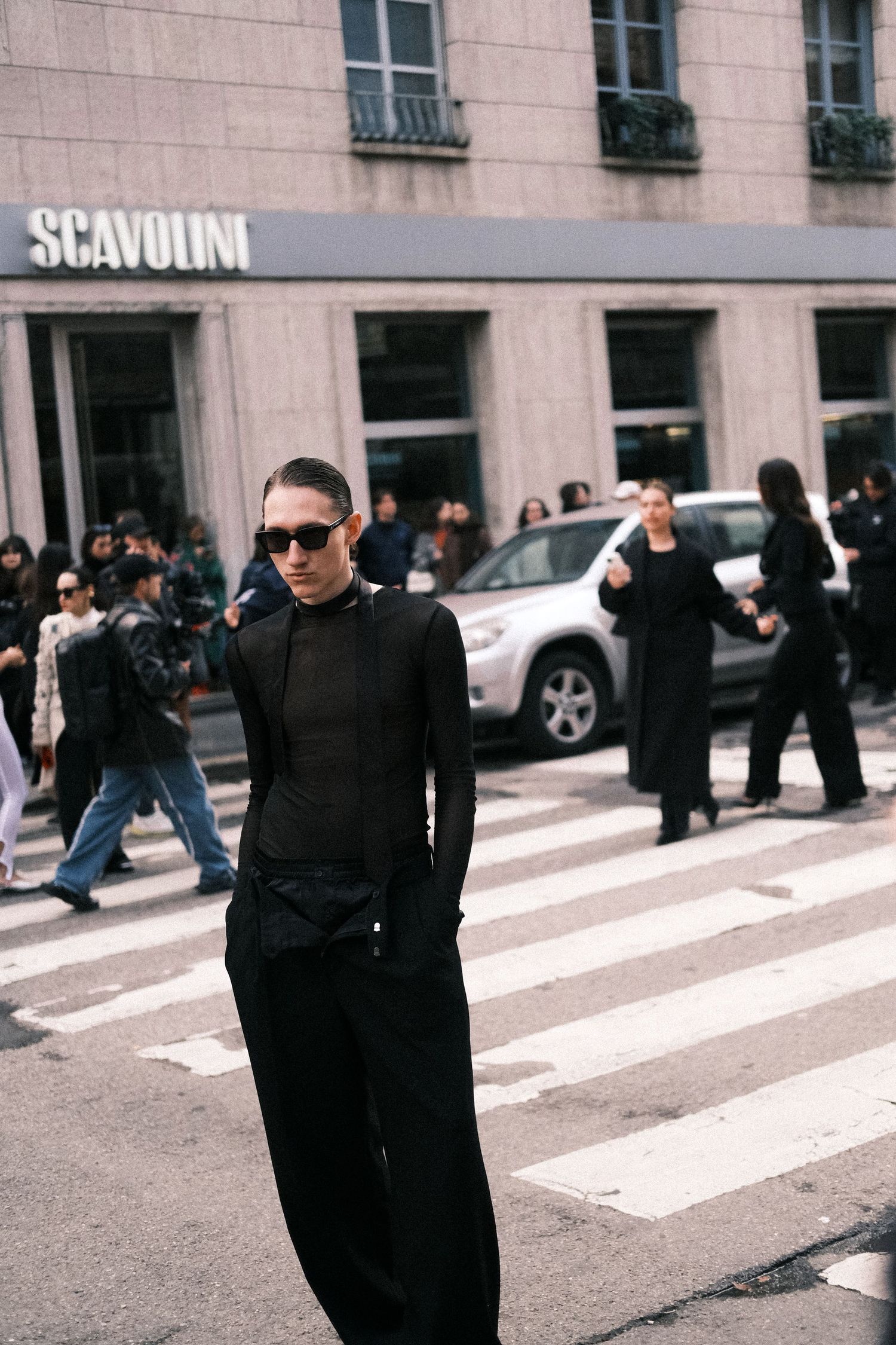 A sequence of black and white street photos showing a figure in dark clothing walking across a crosswalk in an urban setting.