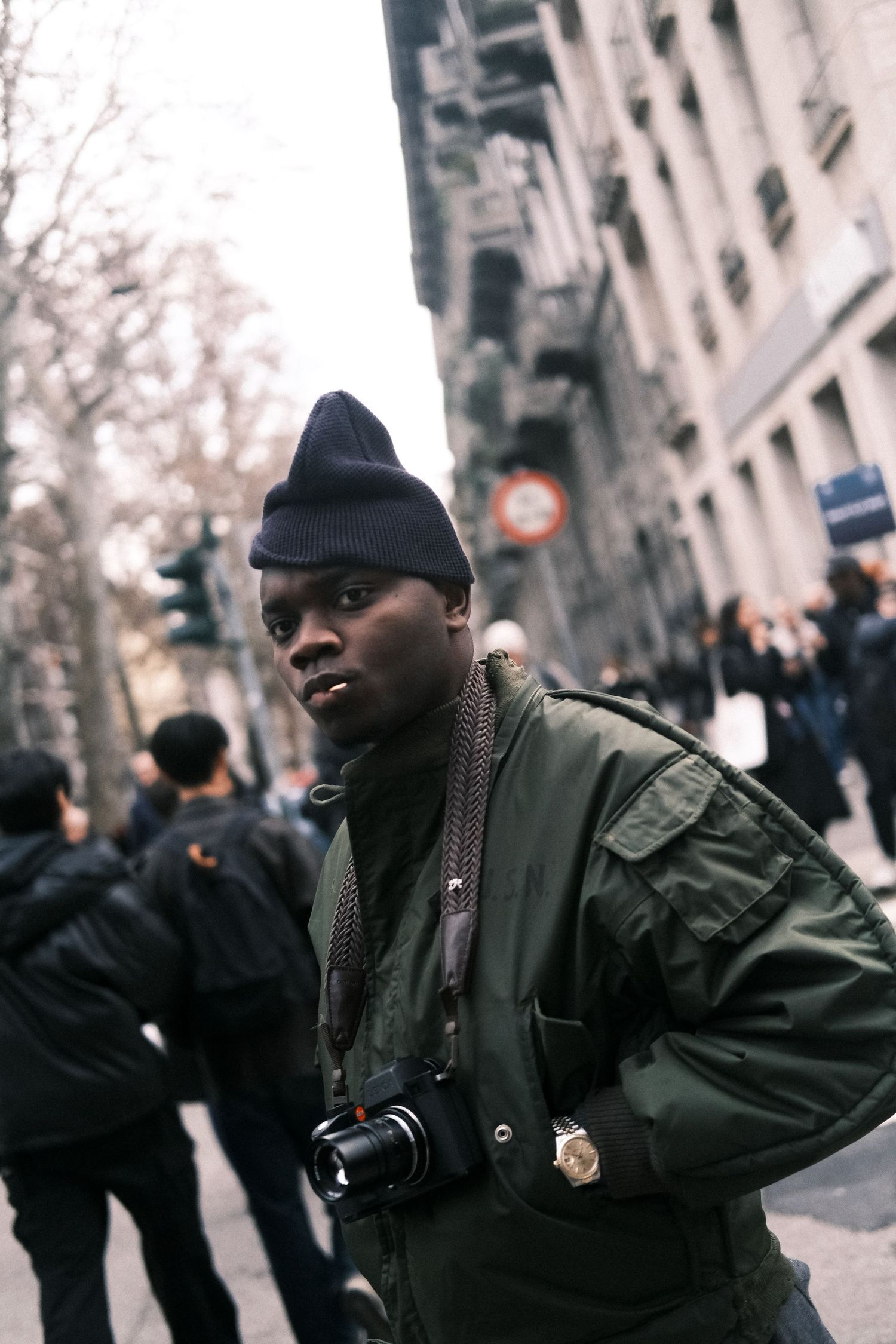 A sequence of four urban street photos showing a person in a dark winter coat and knit cap on a city sidewalk.