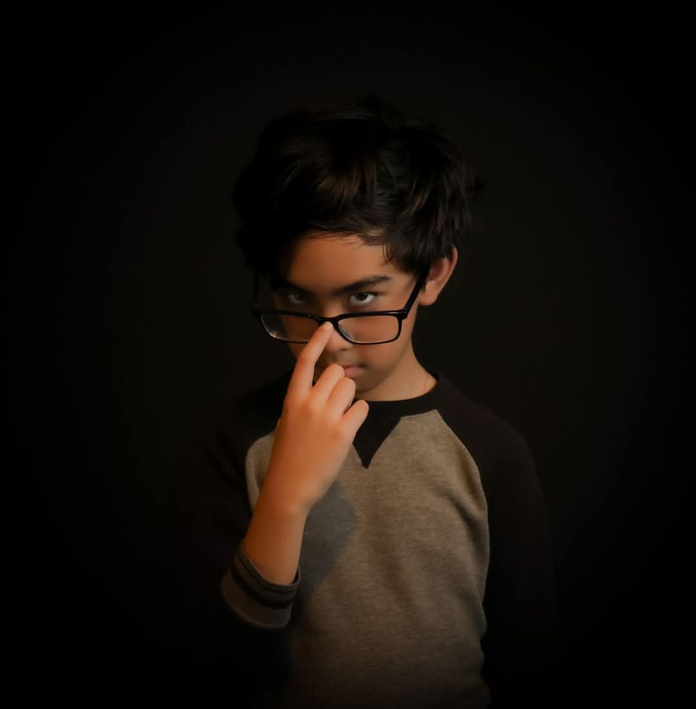 Low-key portrait of a person in glasses against a dark background.