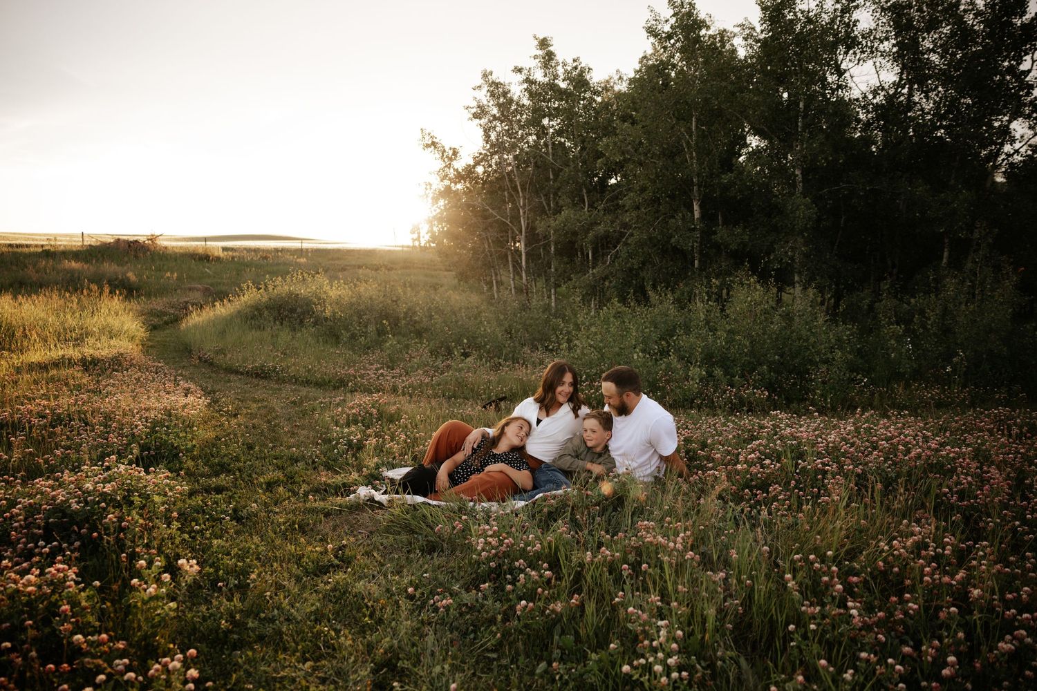A family plays together near a white door while sitting on the floor with cozy blankets.