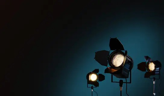 Professional lighting equipment silhouetted against a dark blue sky.