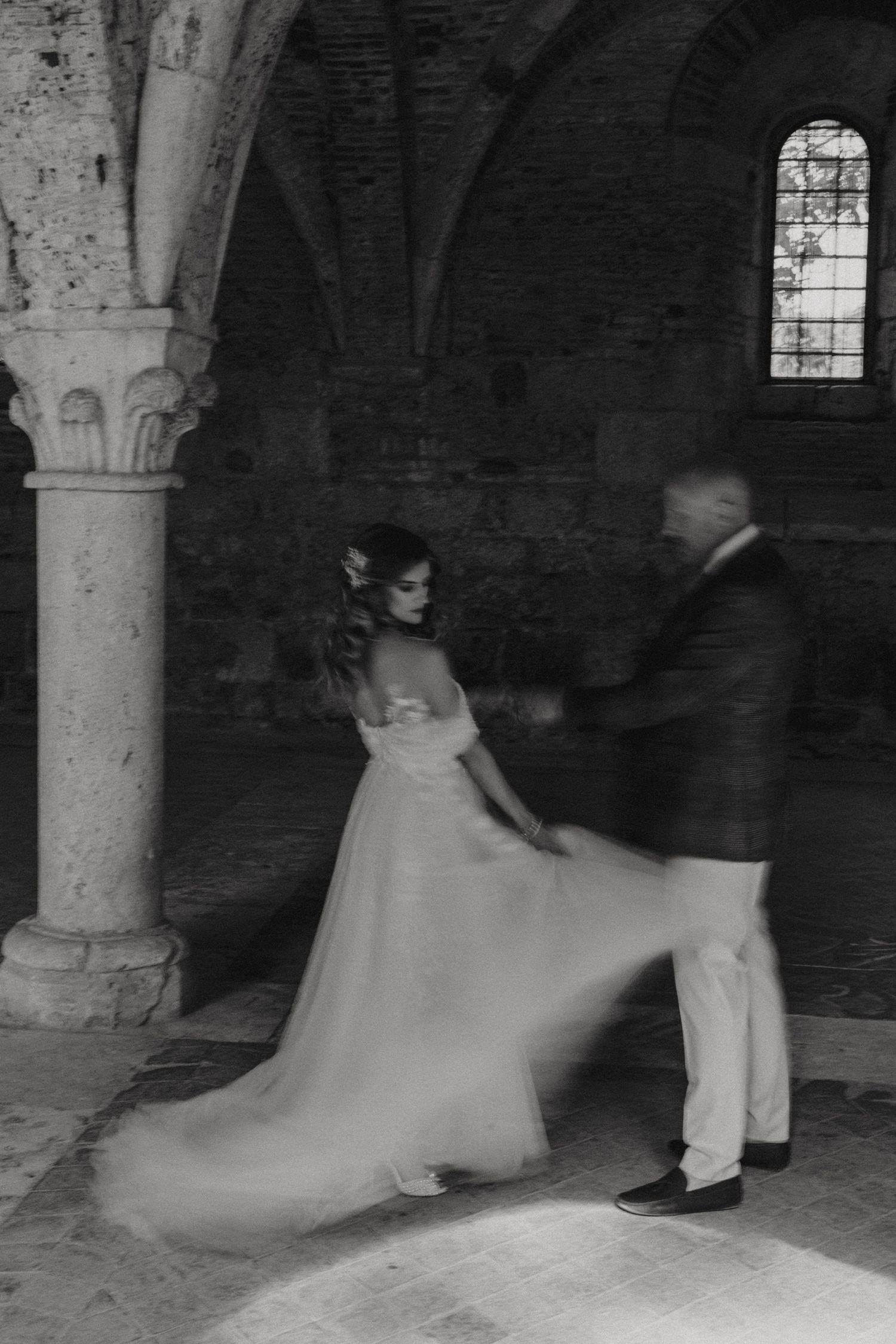 Artistic black and white photo of couple dancing in historic stone church interior. Image taken by Lincolnshire photographers.