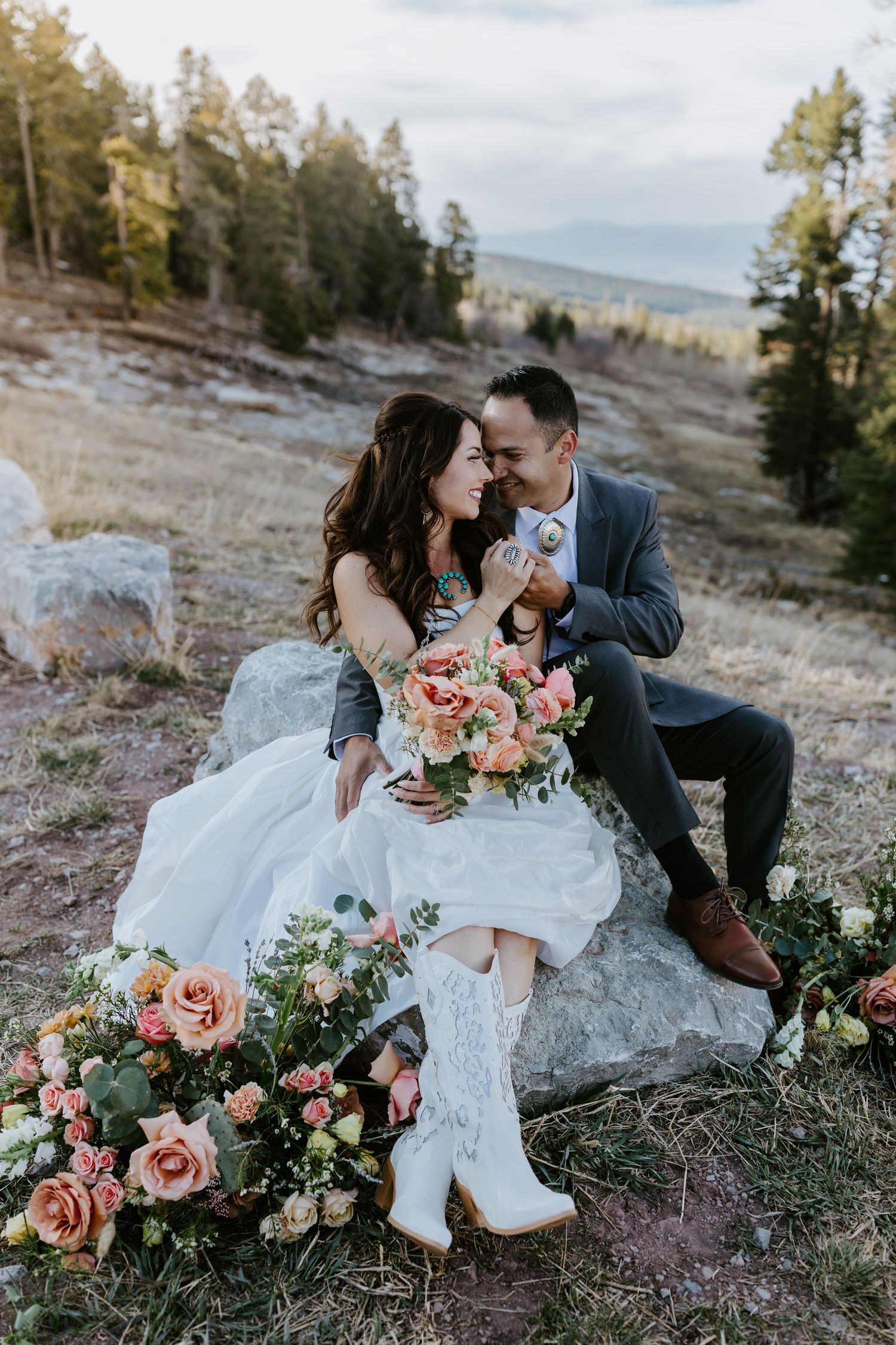 Newlyweds share a romantic moment on a desert path surrounded by sage brush at sunset.