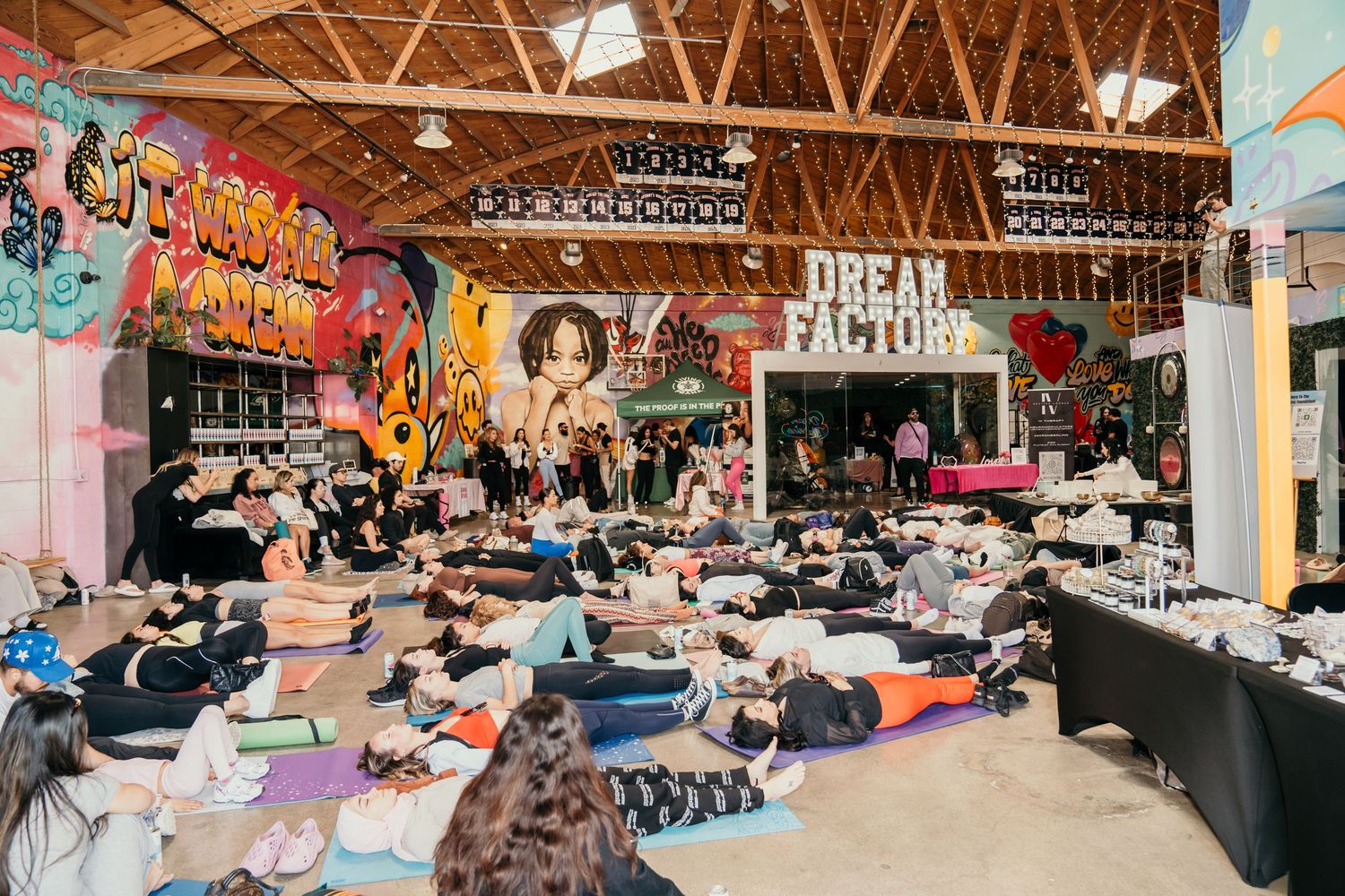 Yoga class participants lying on mats in a colorful studio with graffiti-style artwork on walls.