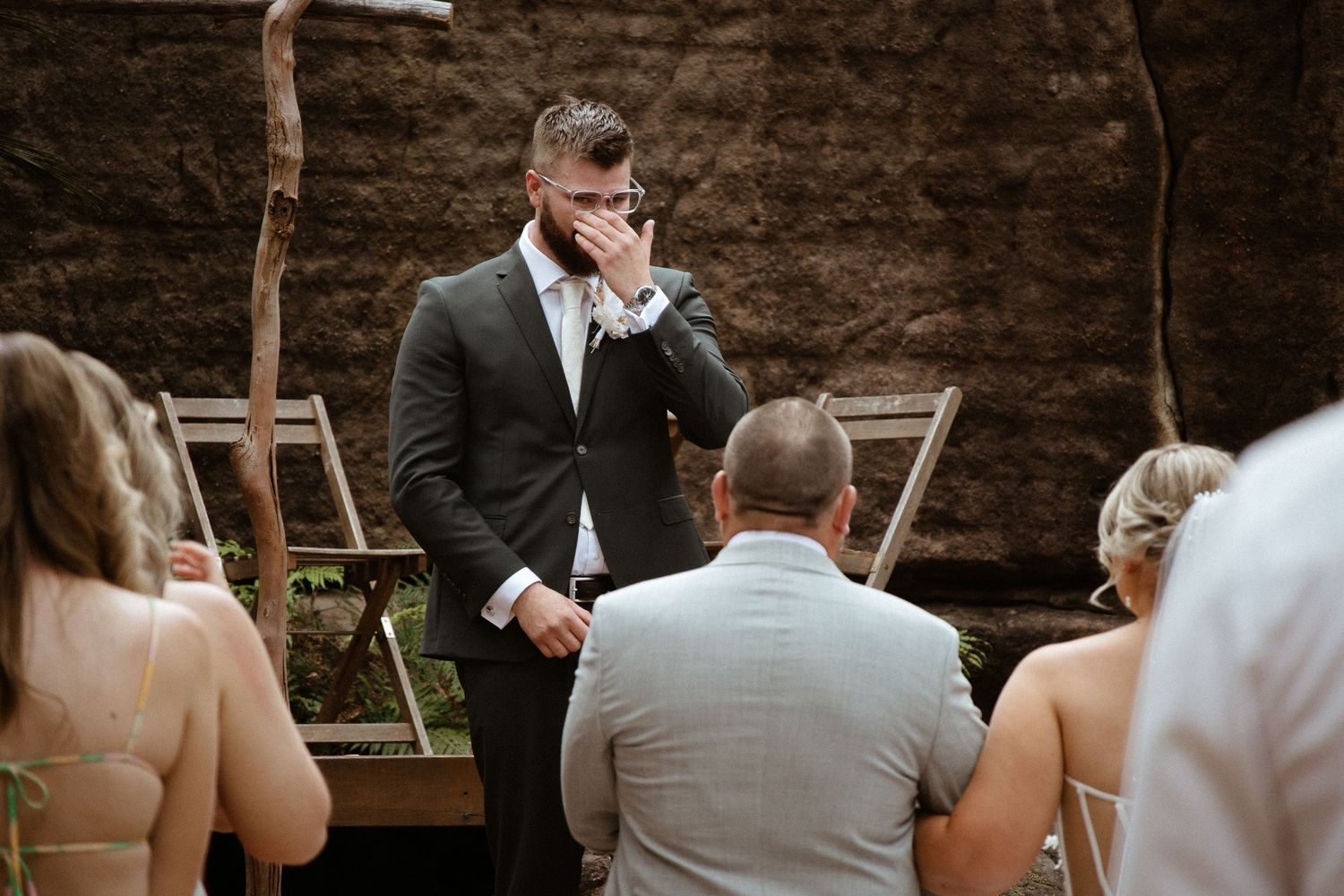 An emotional moment during an outdoor wedding ceremony among rocks and cliffs.