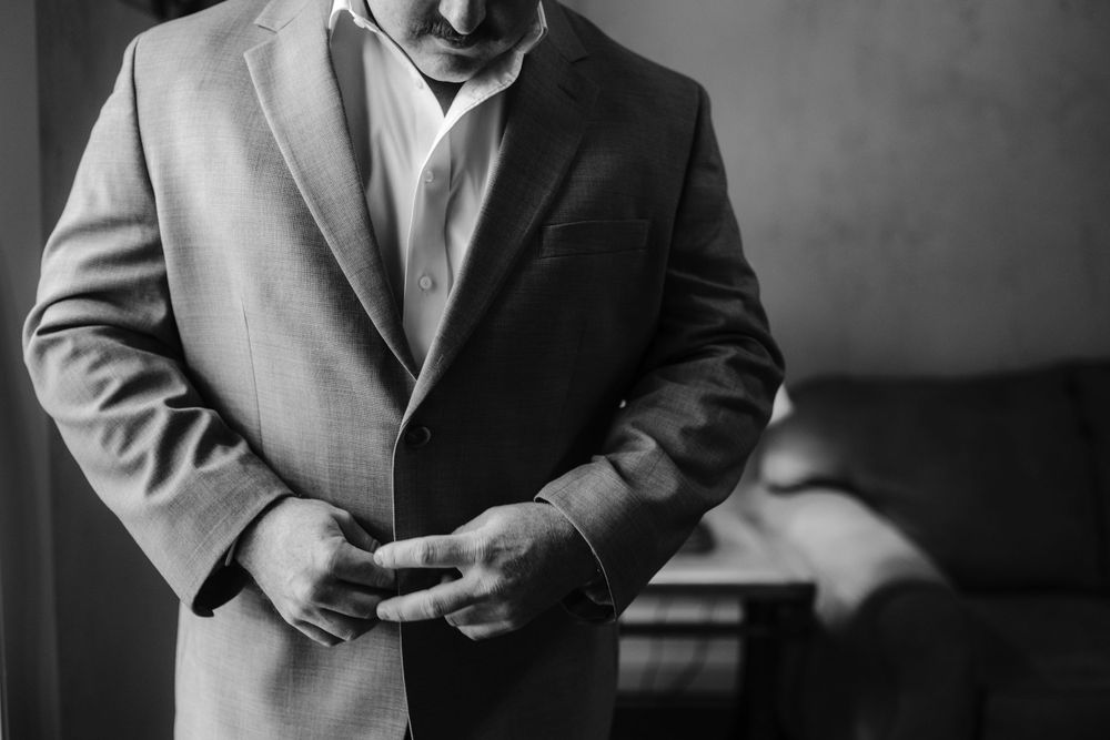Close up of a person adjusting a grey suit jacket in formal attire.