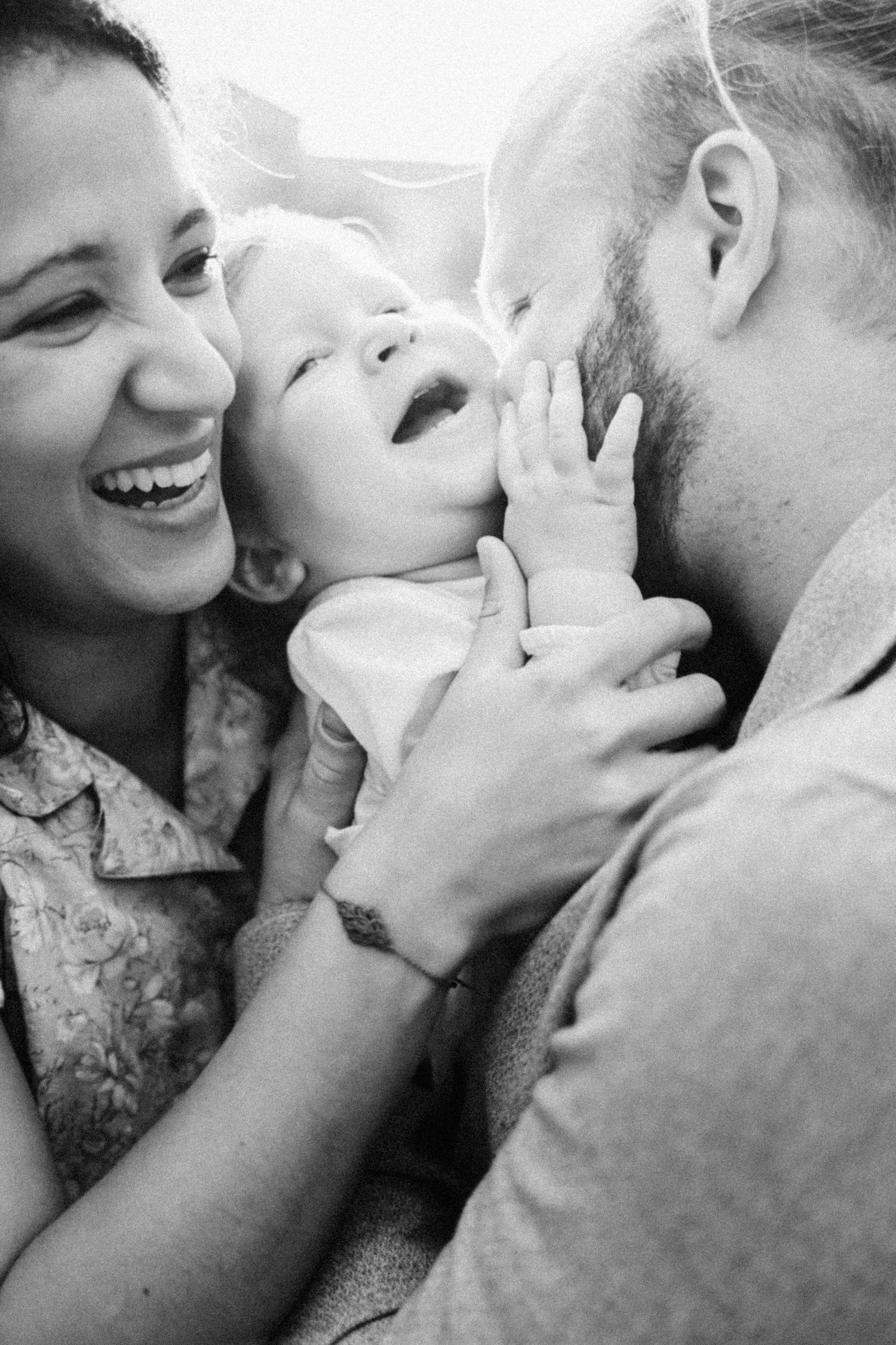 Black and white portrait of joyful family moment with laughing baby.