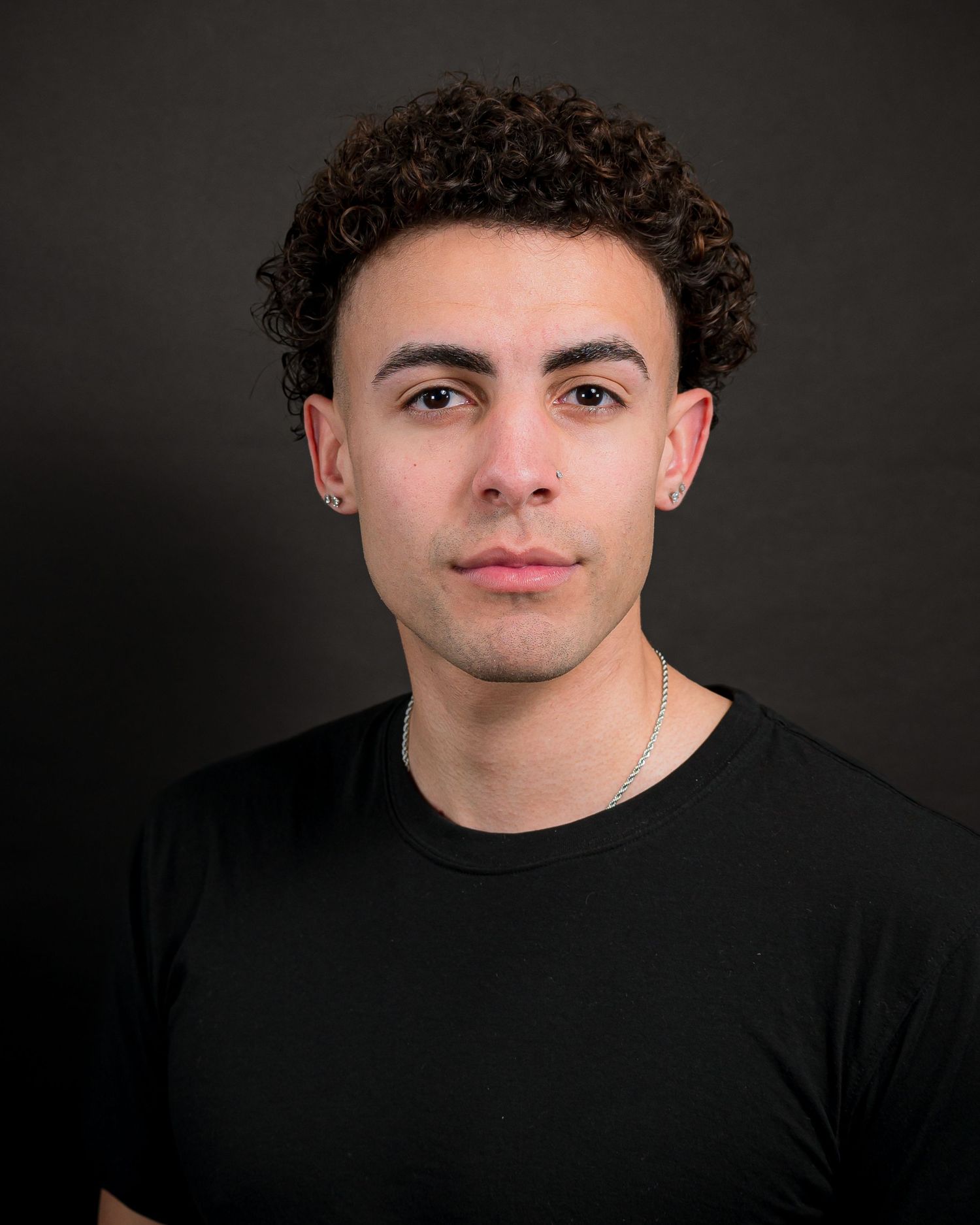 Professional portrait in black shirt against dark studio background.