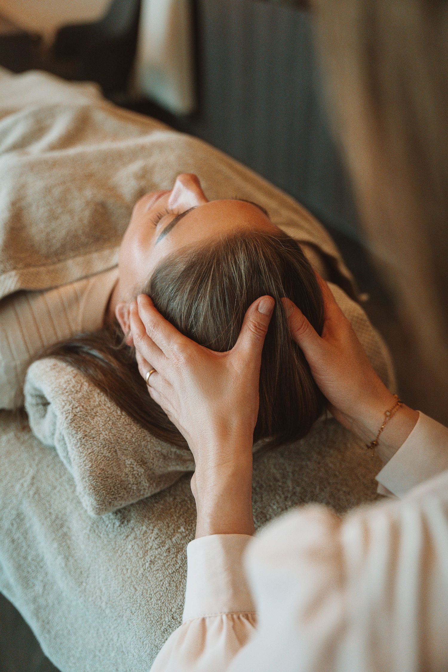 Person receiving a relaxing head massage treatment while lying down on a spa table with soft towels.
