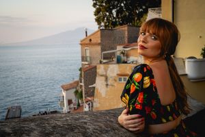 Looking out over the Mediterranean Sea at sunset from a balcony in Positano, Italy wearing a floral dress.