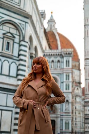 Fashionable person in a tan trench coat poses in front of the iconic Florence Duomo cathedral in Italy.