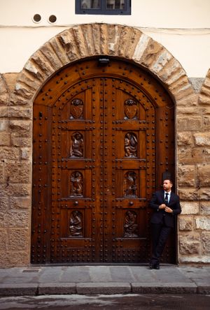 A massive ornate wooden door with iron studs and carved panels set in a stone archway of an old European building.