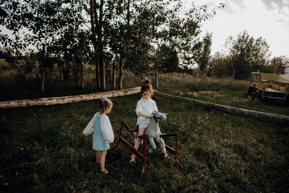 Children playing outdoors in rustic setting with trees.