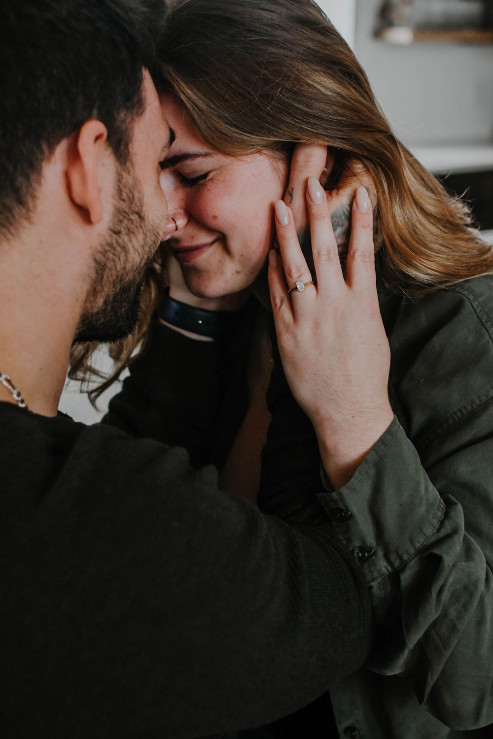 A tender romantic moment between two people sharing an intimate embrace in a dimly lit setting.