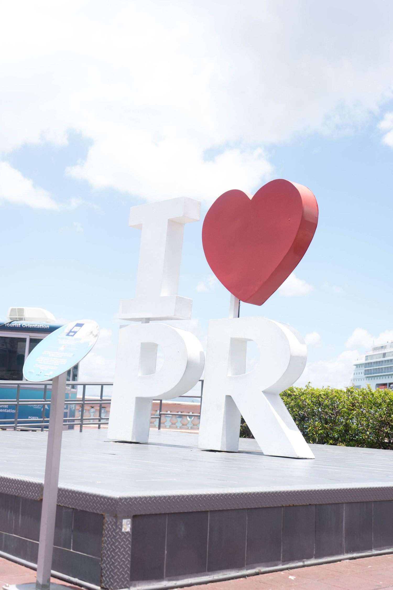 I Love PR large outdoor sign with red heart under blue sky at a Puerto Rico waterfront.