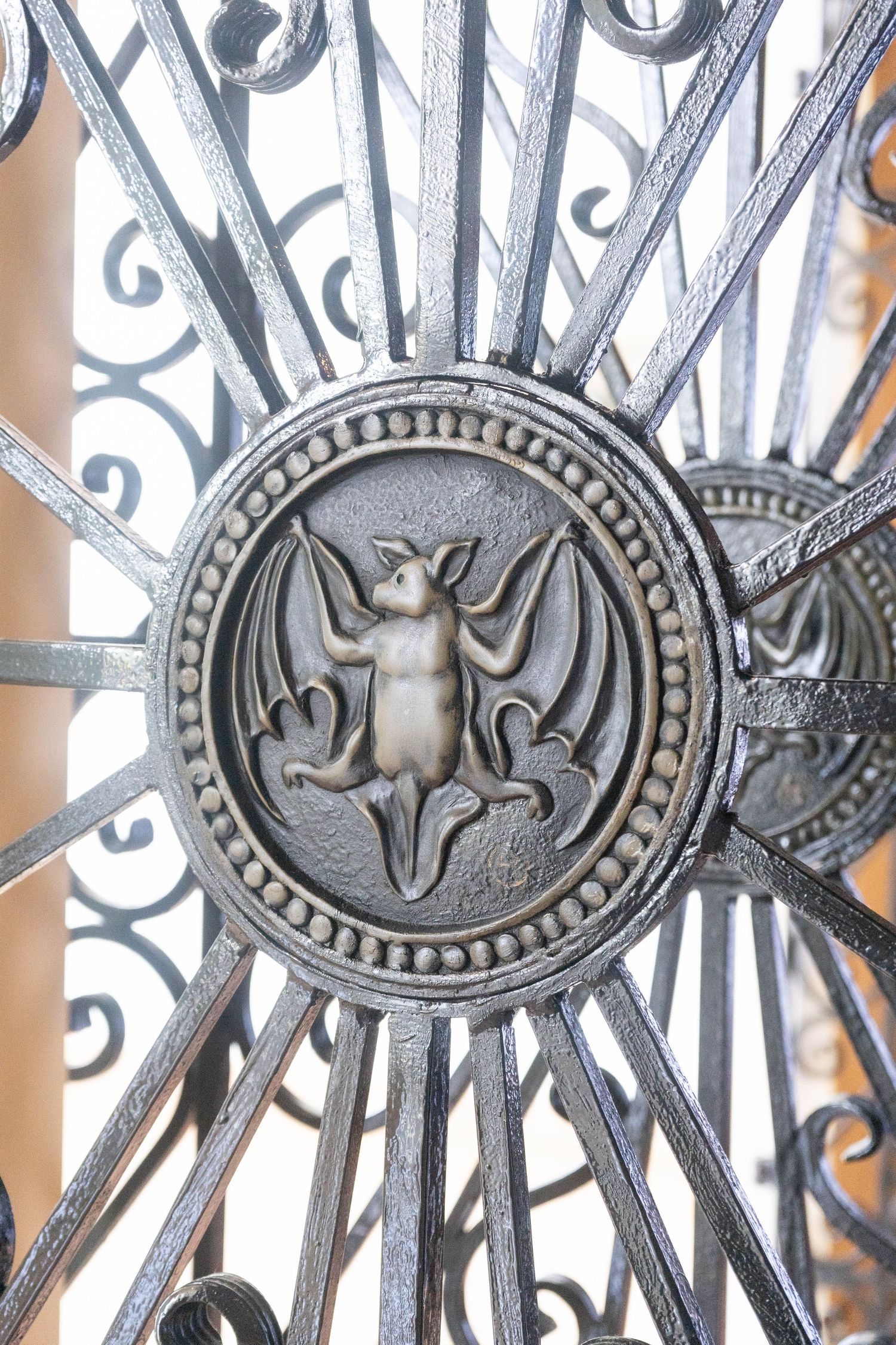 Ornate wrought iron gate medallion featuring a bat emblem, the iconic Bacardi rum symbol.