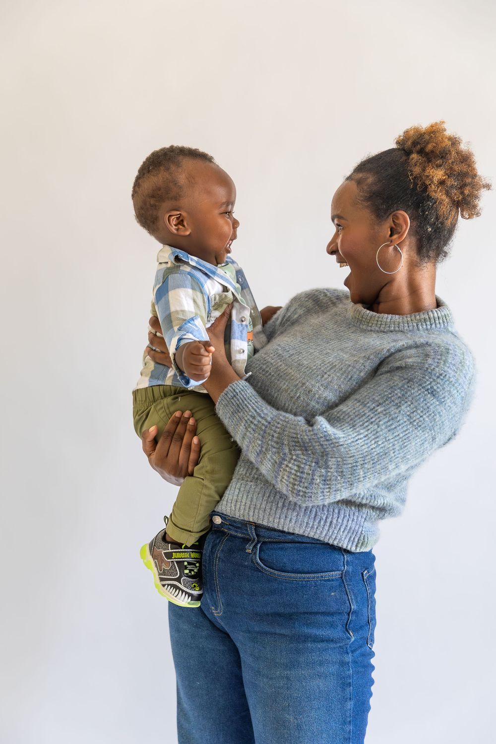 A joyful moment of parent and toddler sharing a laugh while playing together against a light background.