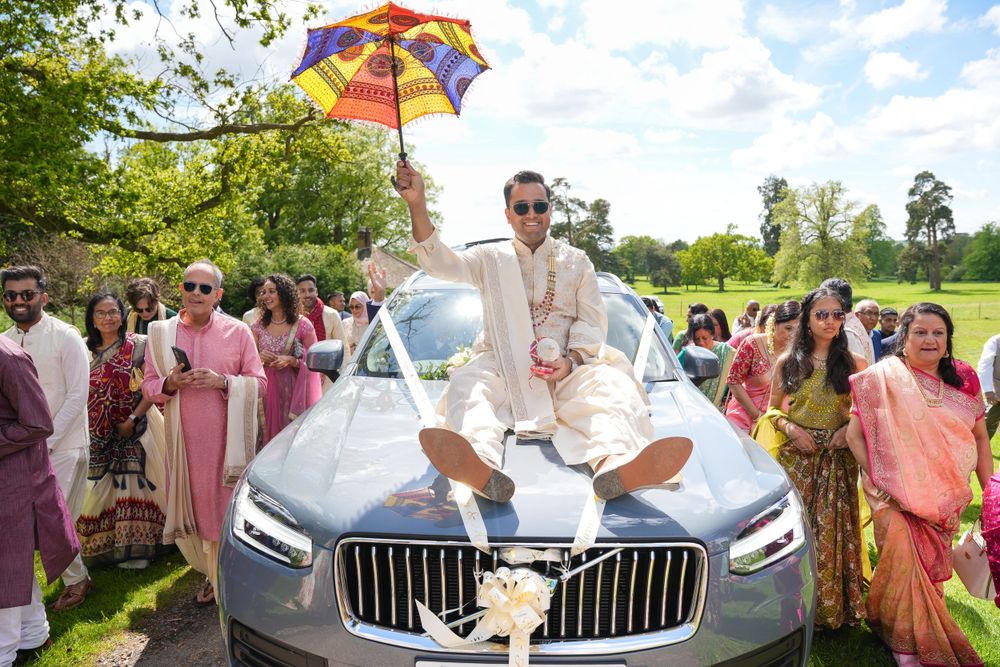 Celebratory scene with a colorful umbrella atop a luxury car during a wedding celebration. Shrubland Palace