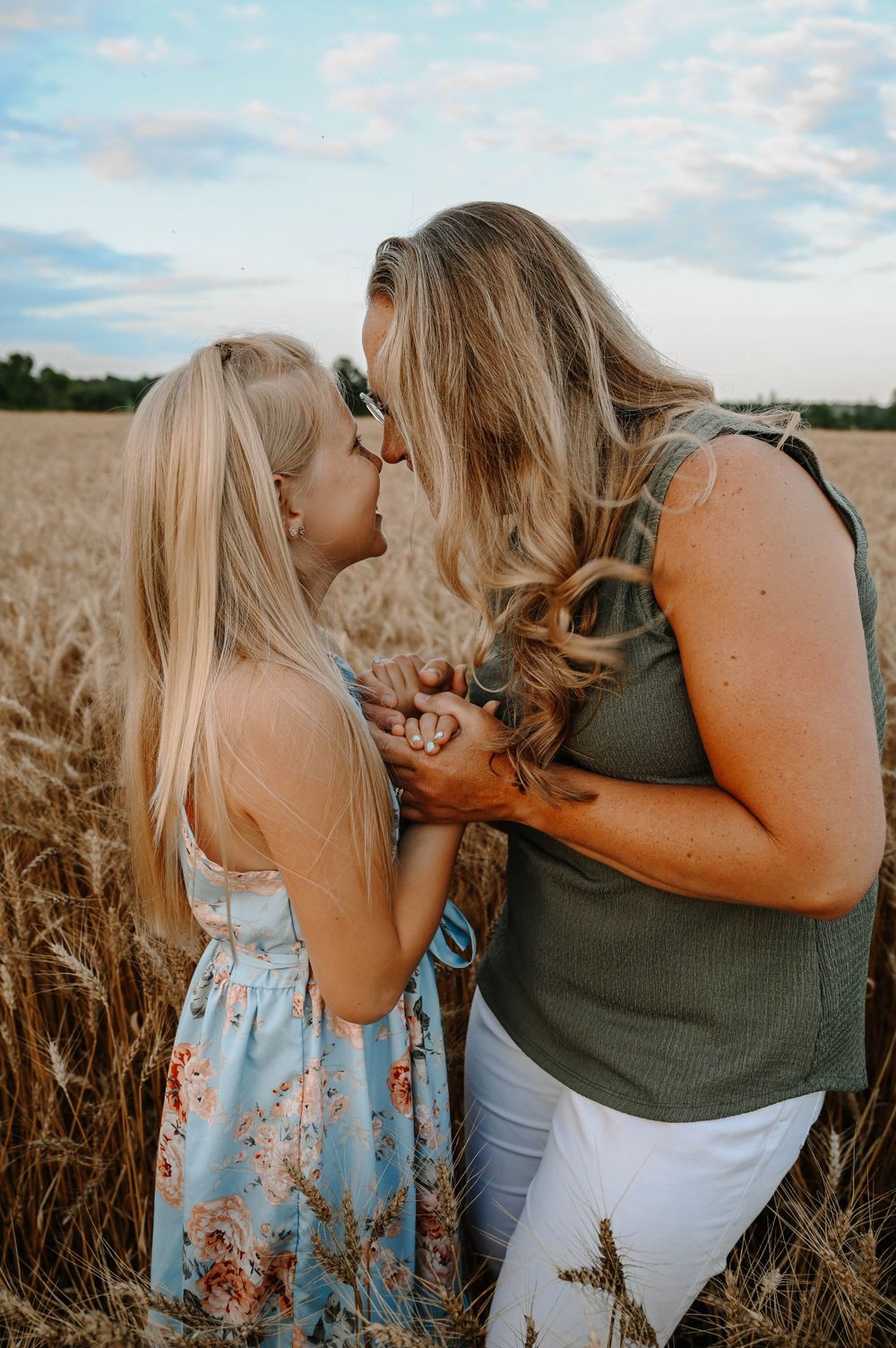 A tender moment shared between two people in a golden wheat field at sunset, wearing casual summer attire.