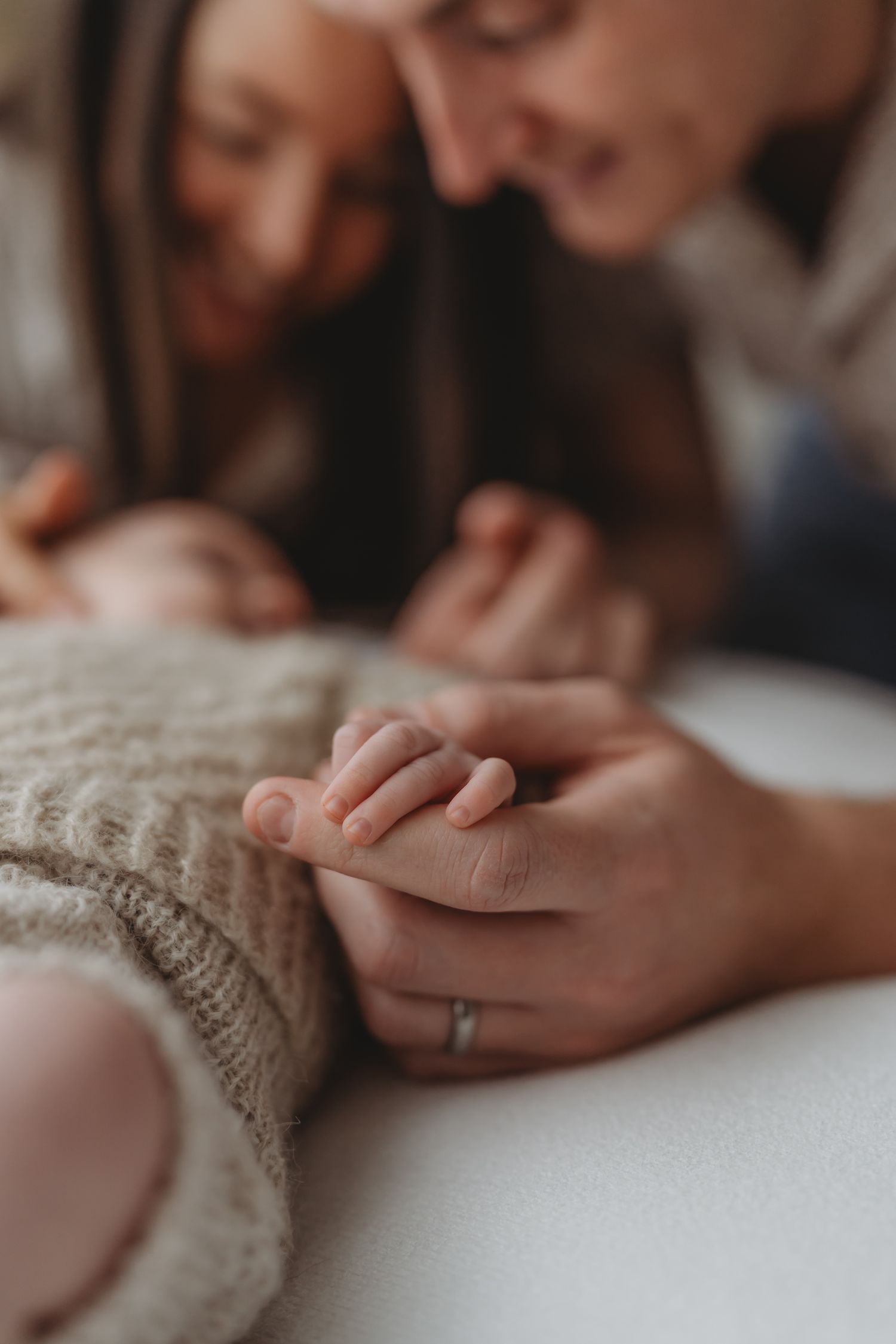 Close-up photo capturing a tiny baby's hand being gently held against a cozy knitted sweater.