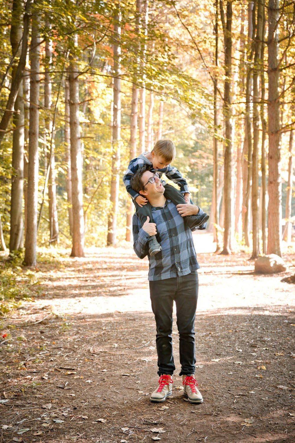 A tender moment between parent and child in an autumn forest path illuminated by golden sunlight.