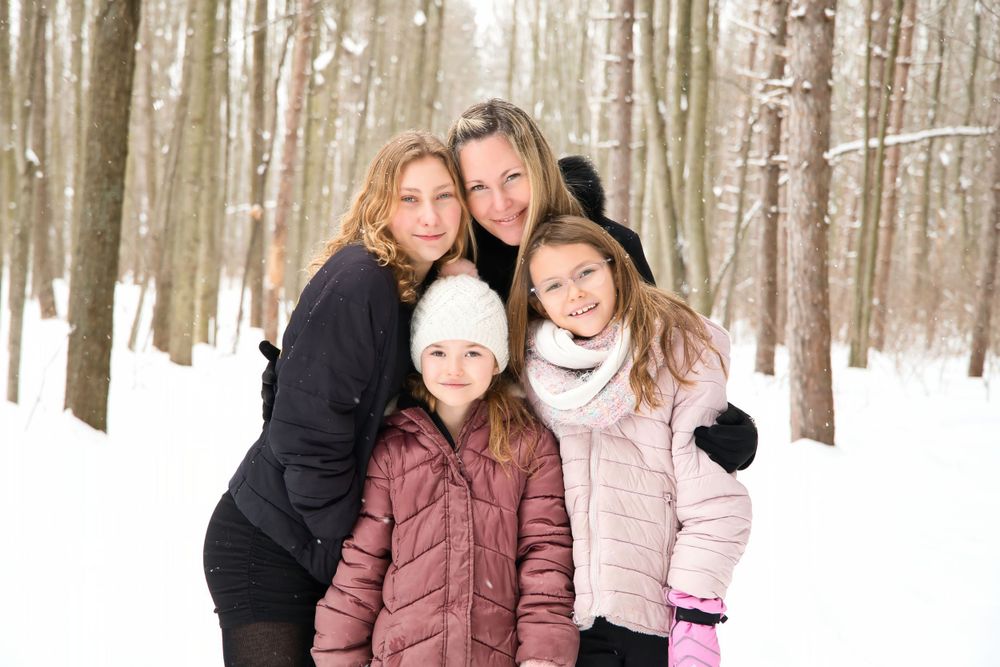A casual group photo in a snowy winter forest with evergreen trees.