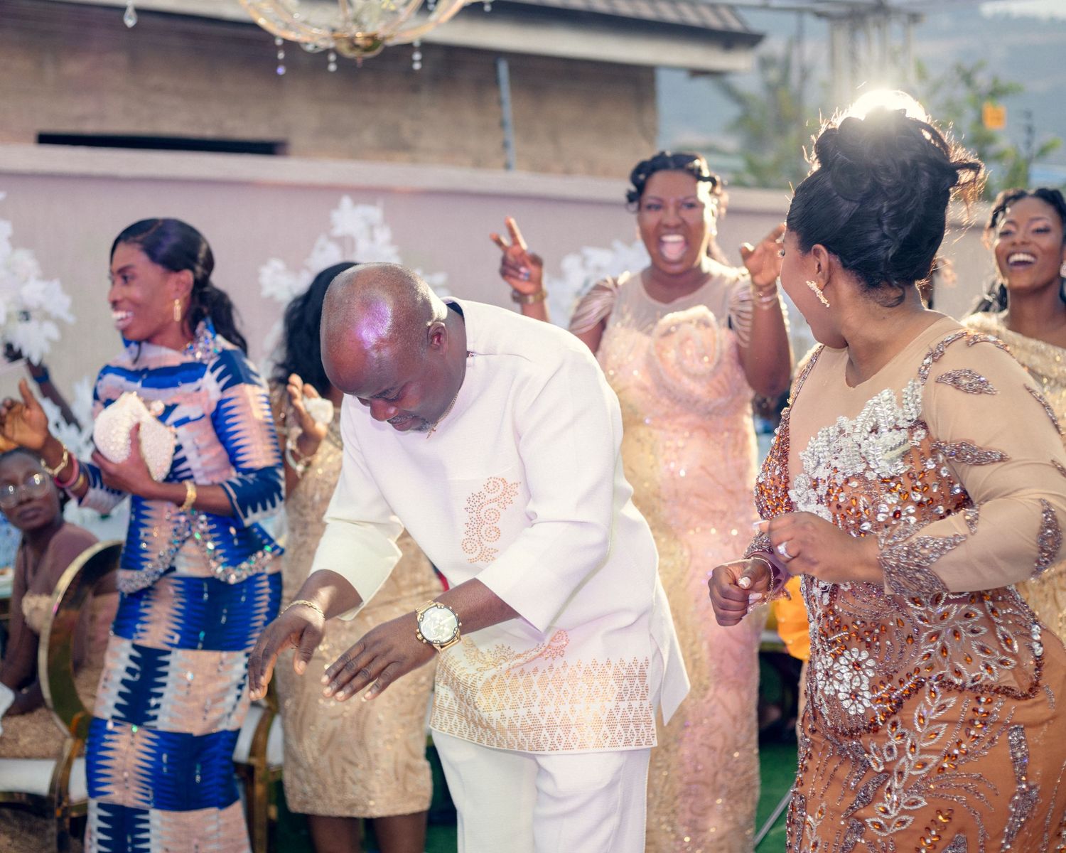 Wedding guests dancing and celebrating in traditional African prints and formal attire.