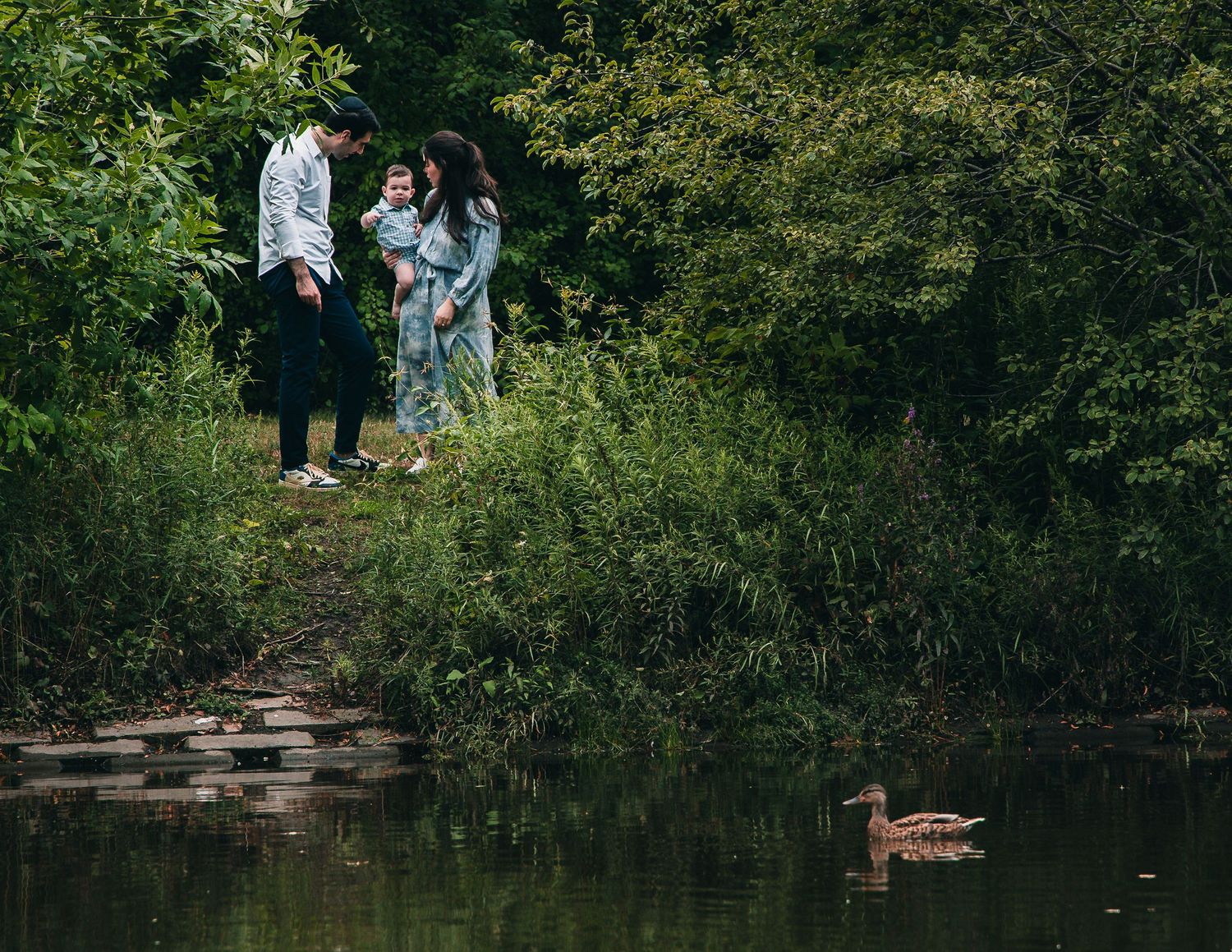 Scenic view of a tranquil pond surrounded by green foliage in a natural outdoor setting.