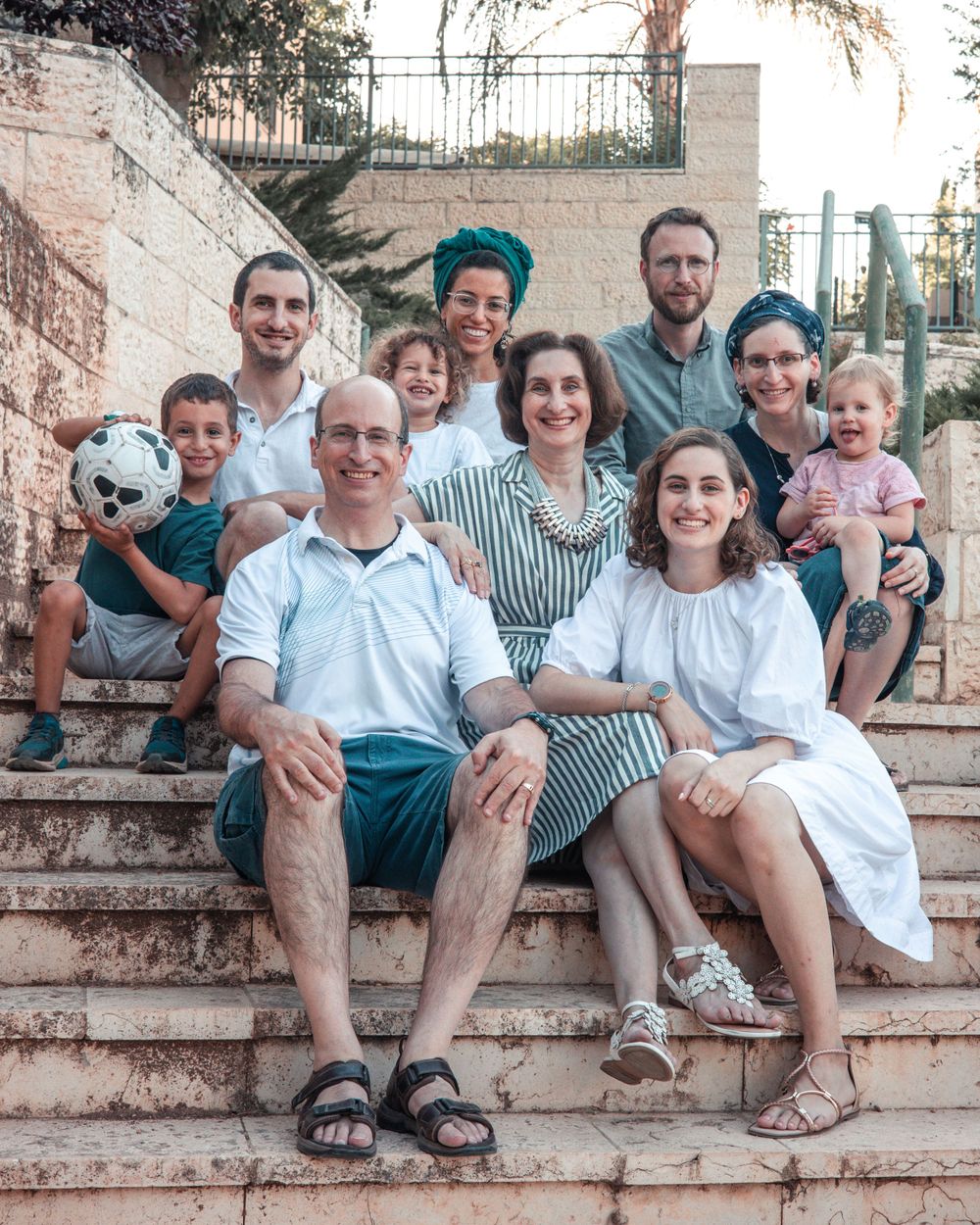 Multi-generational family gathered on stone steps for casual outdoor portrait.